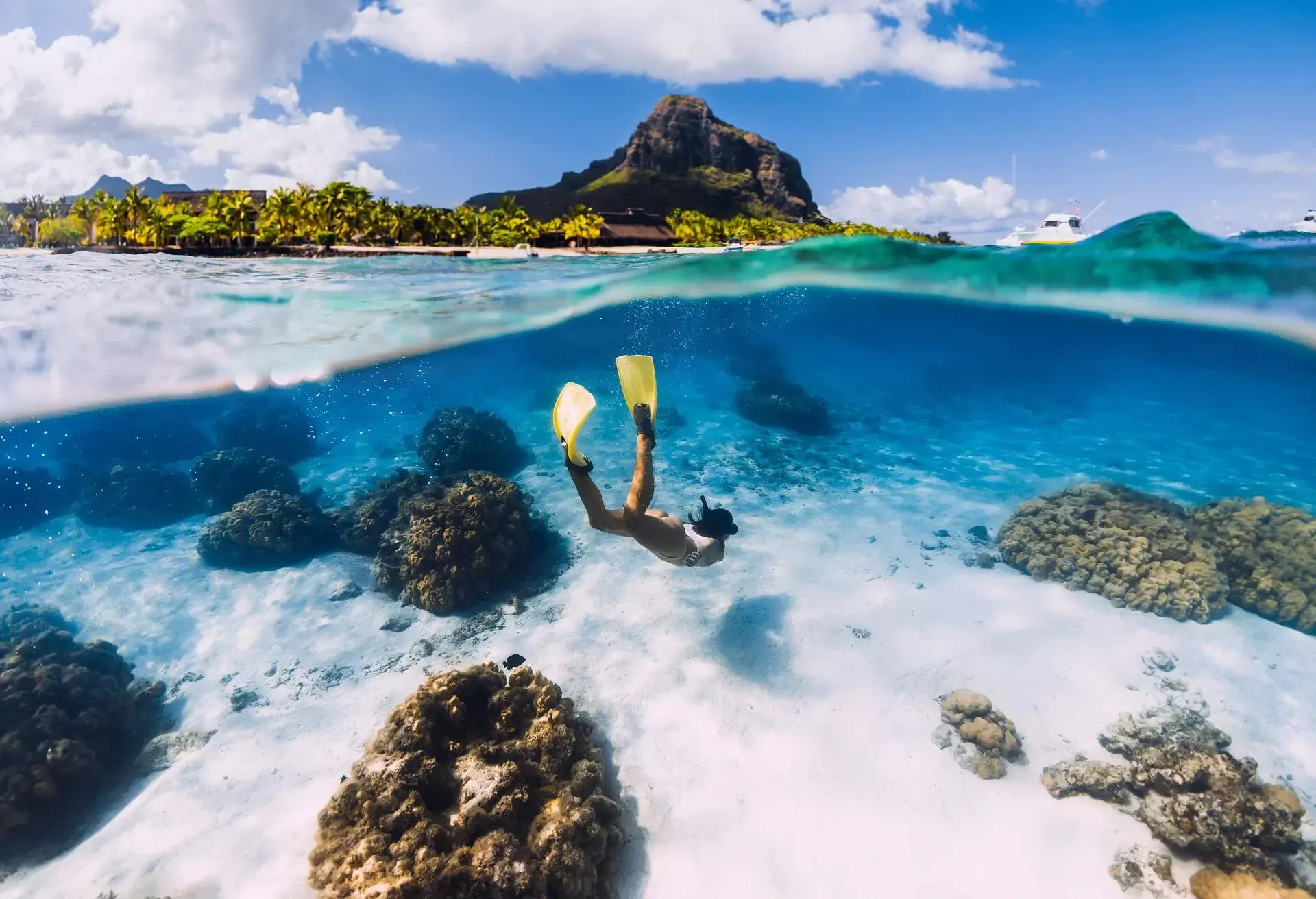 Woman freediver glides over sandy sea with fins in transparent ocean. Freediving in Mauritius