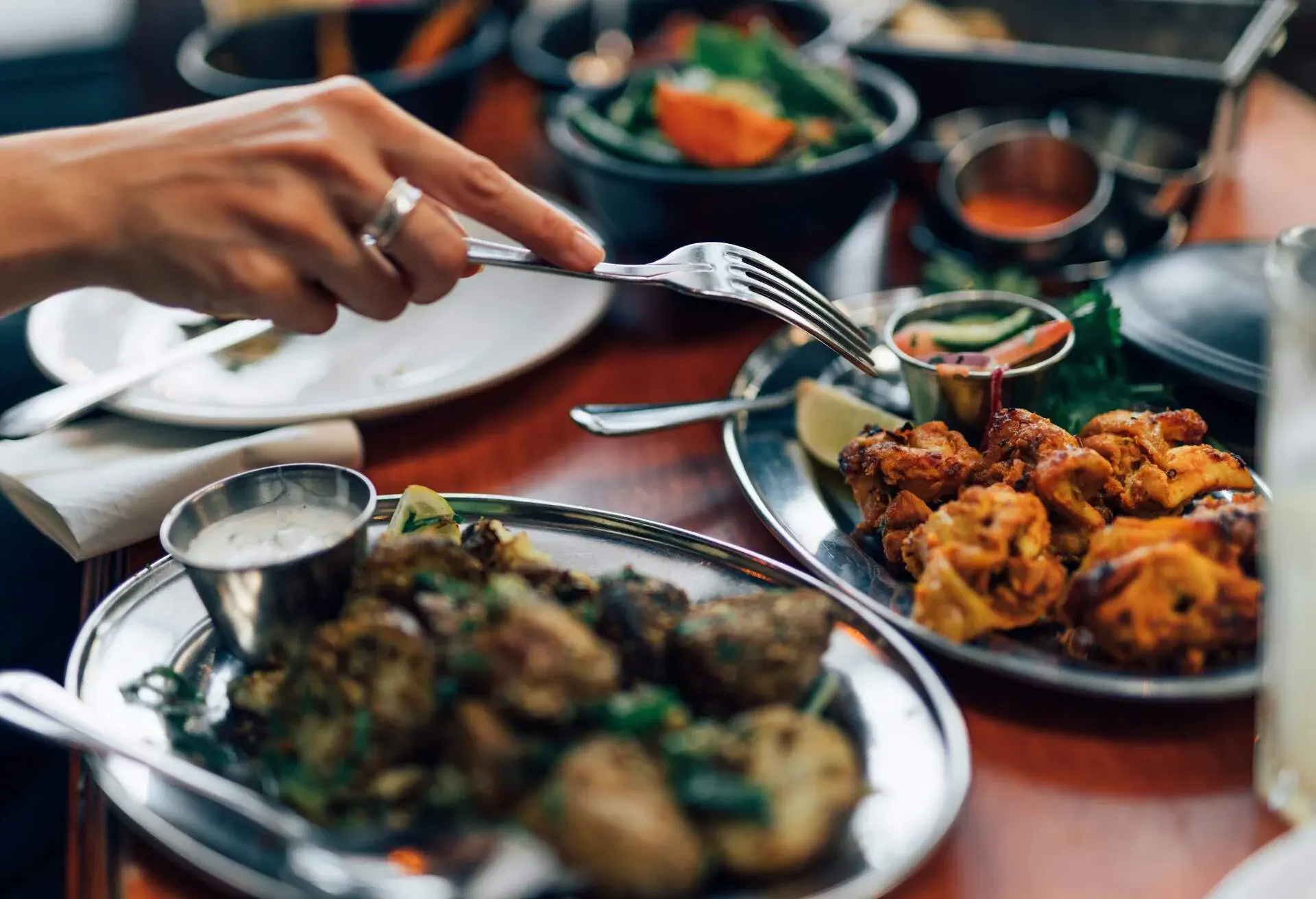 Indian grilled chicken (Chicken Tikka), roast spiced potatoes, yoghurt raita, nan bread and a bowl of vegetables.