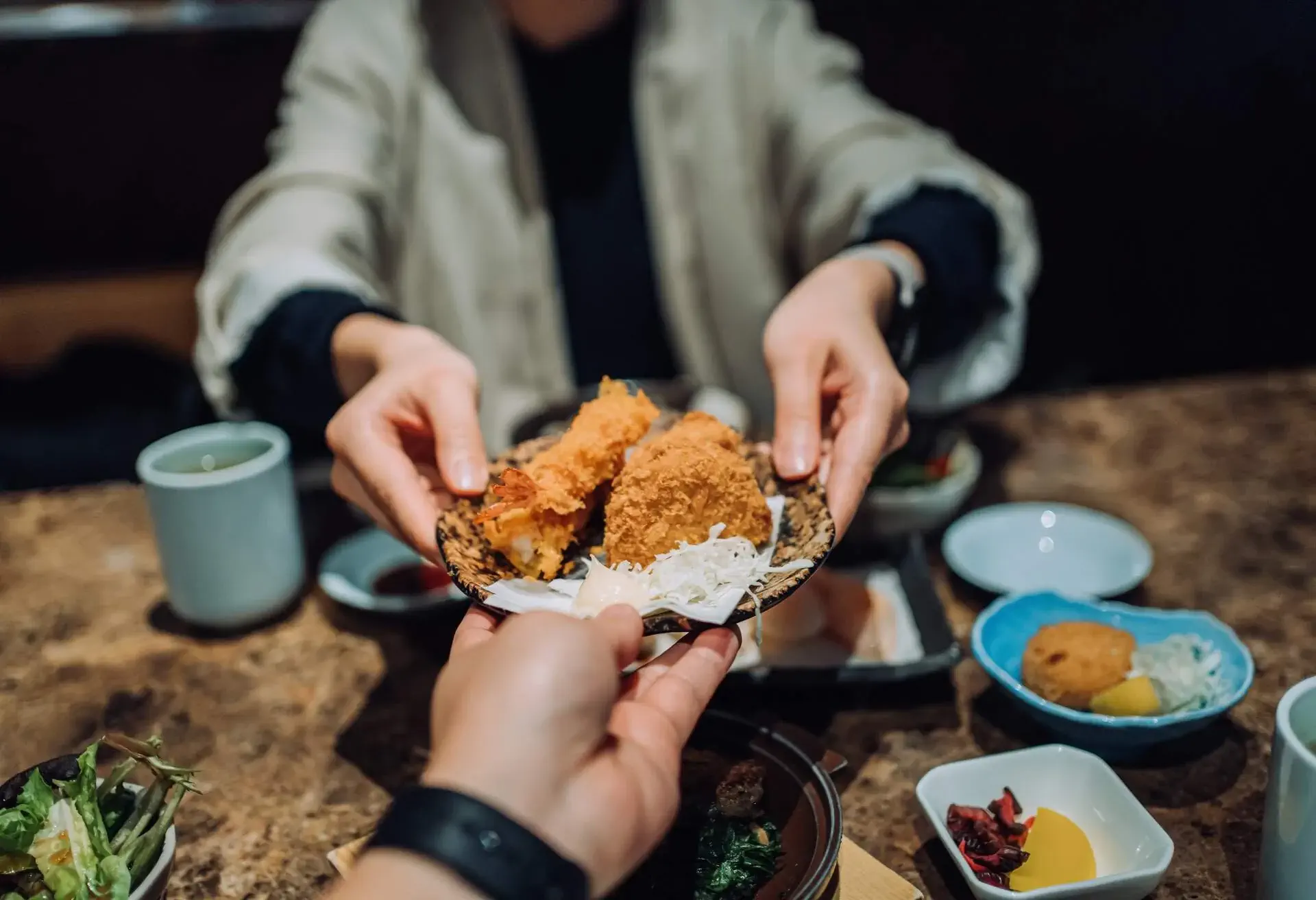 Asian couple enjoying delicate Japanese cuisine with assorted sushi and seafood tempura freshly served on dining table.