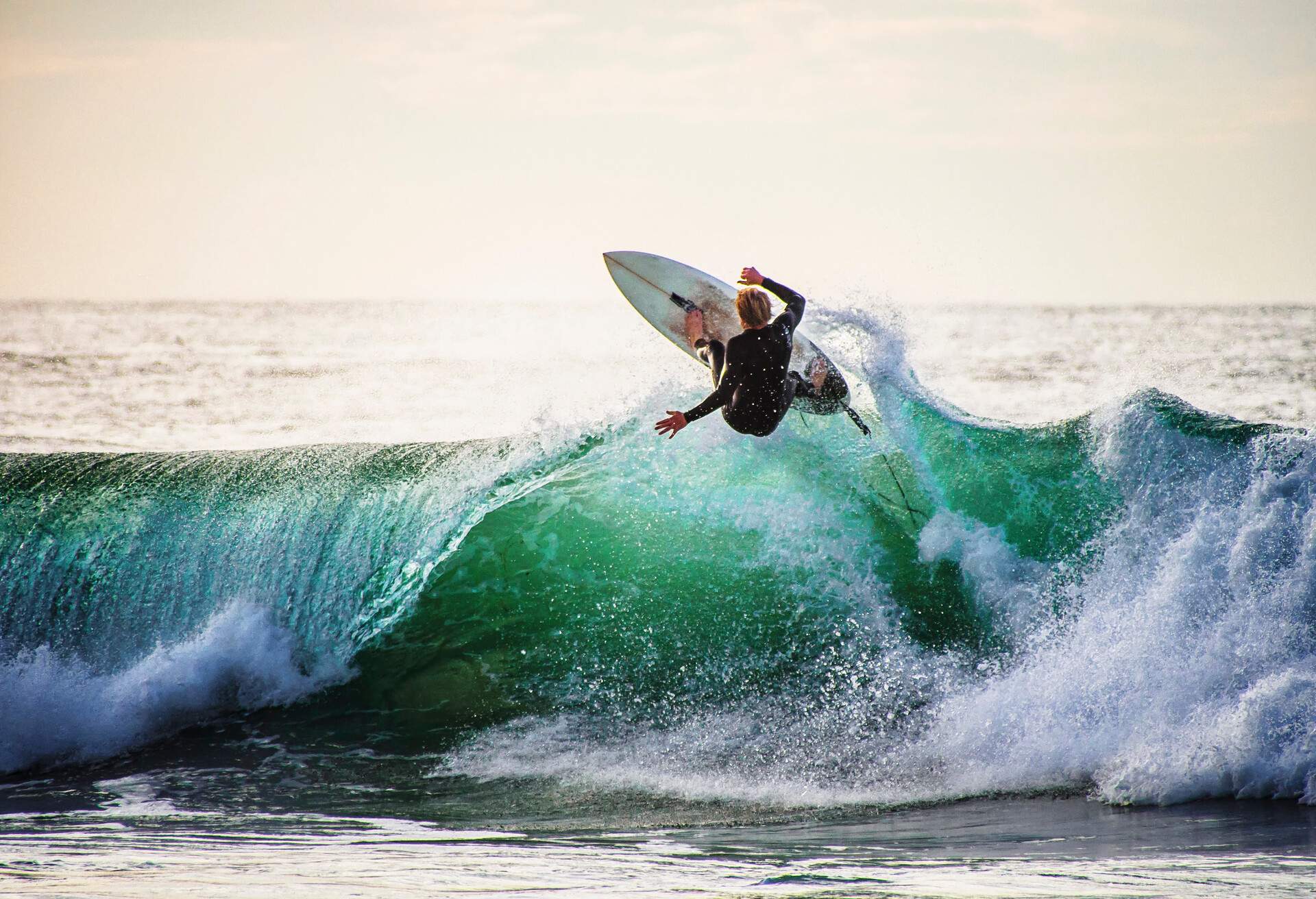 Rear View Of Man Surfing On Waves Against Sky - stock photo