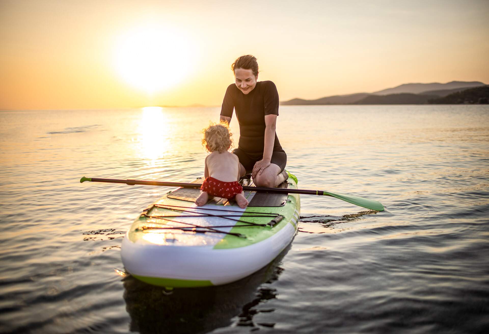 Photo of surfing mum and son enjoys on a paddle board in the sea