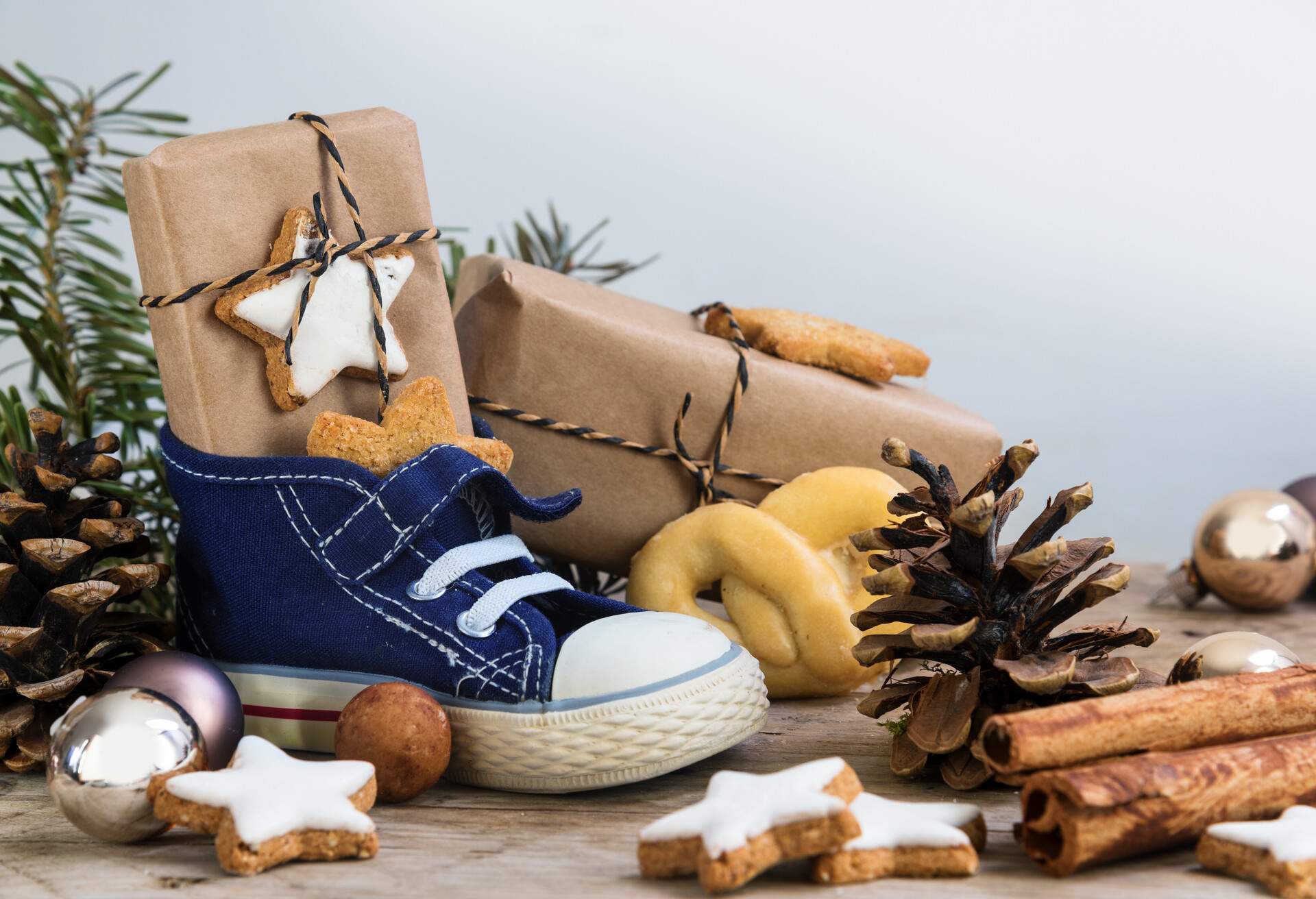 Children's shoe with sweets, gifts and christmas ornaments on rustic wood, german text Am 6. Dezember ist Nikolaustag, meaning  St. Nicholas Day December 6th, selected focus, narrow depth of field