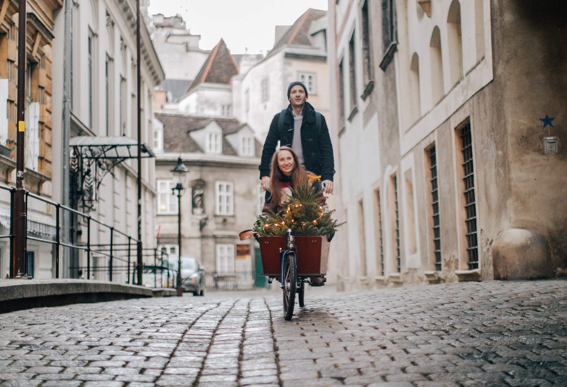 Smiling couple having a fun cargo bike ride while taking their Christmas tree home