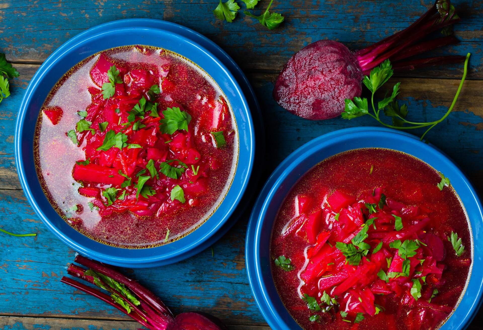 Russian and Ucrainian traditional vegetarian red soup - borsch in blue plates on wooden background. Top view