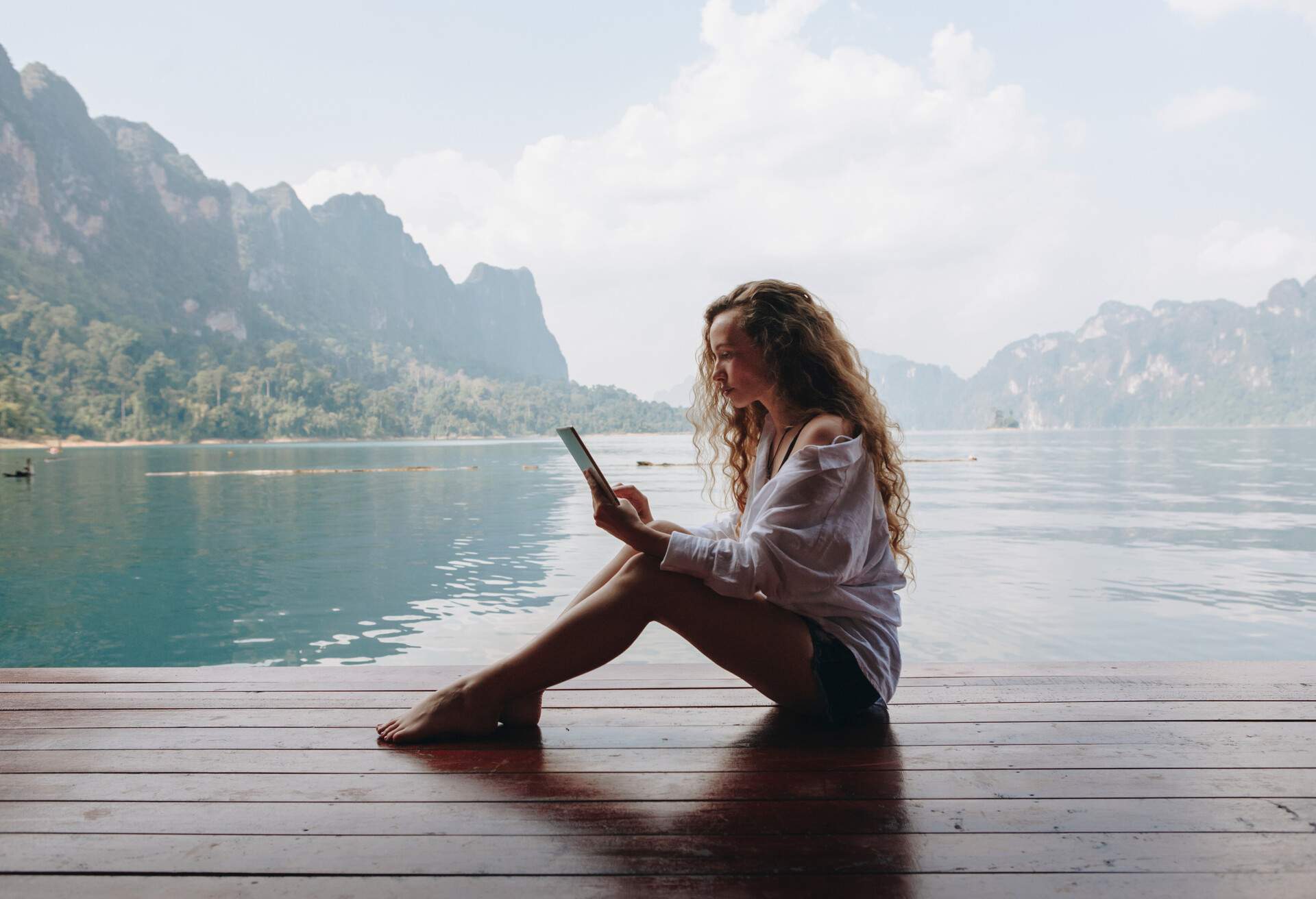 Woman using her phone by a lake