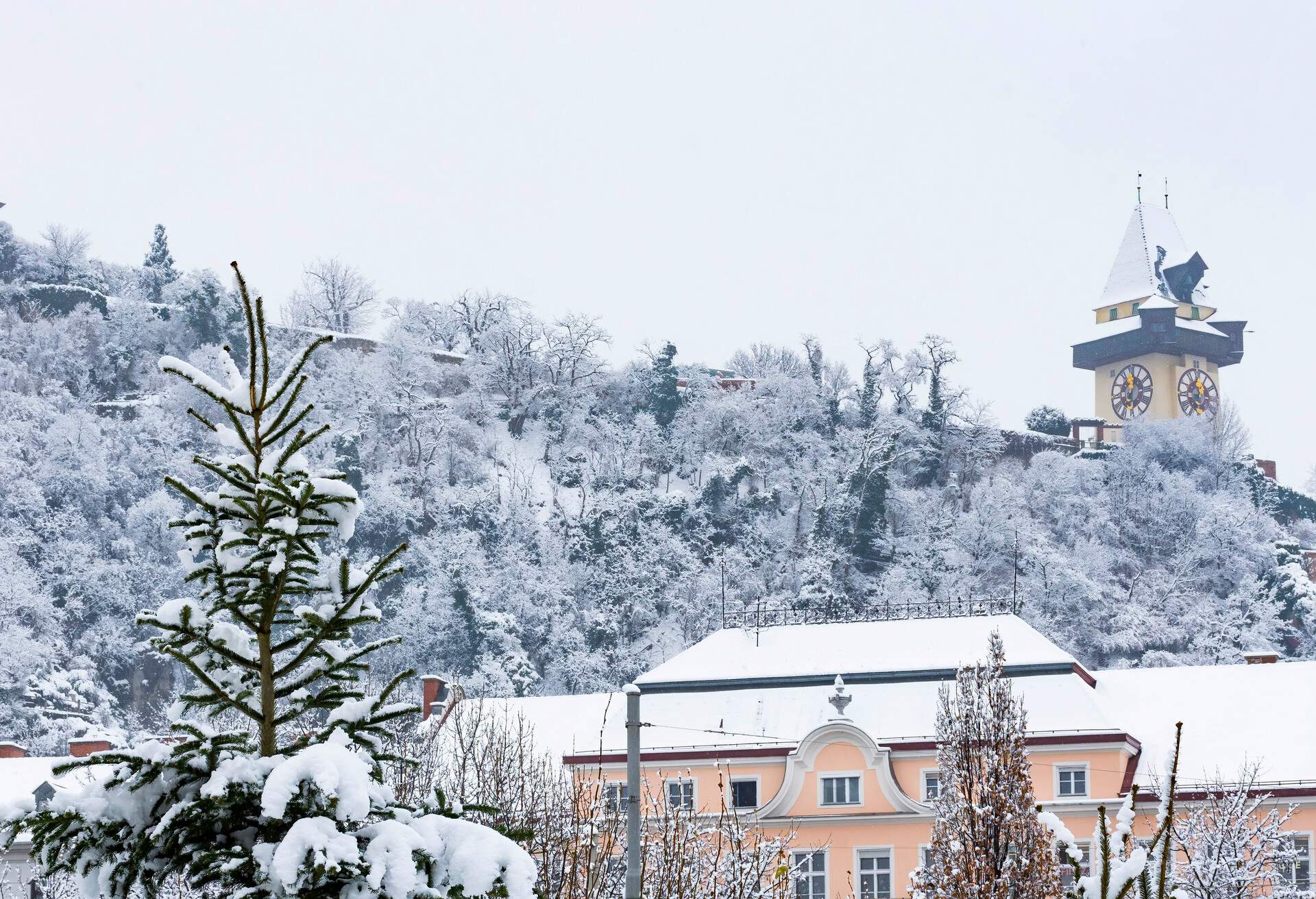 The famous clock tower on Schlossberg hill, in Graz, Steiermark region, Austria, with snow, in winter. Selective focus