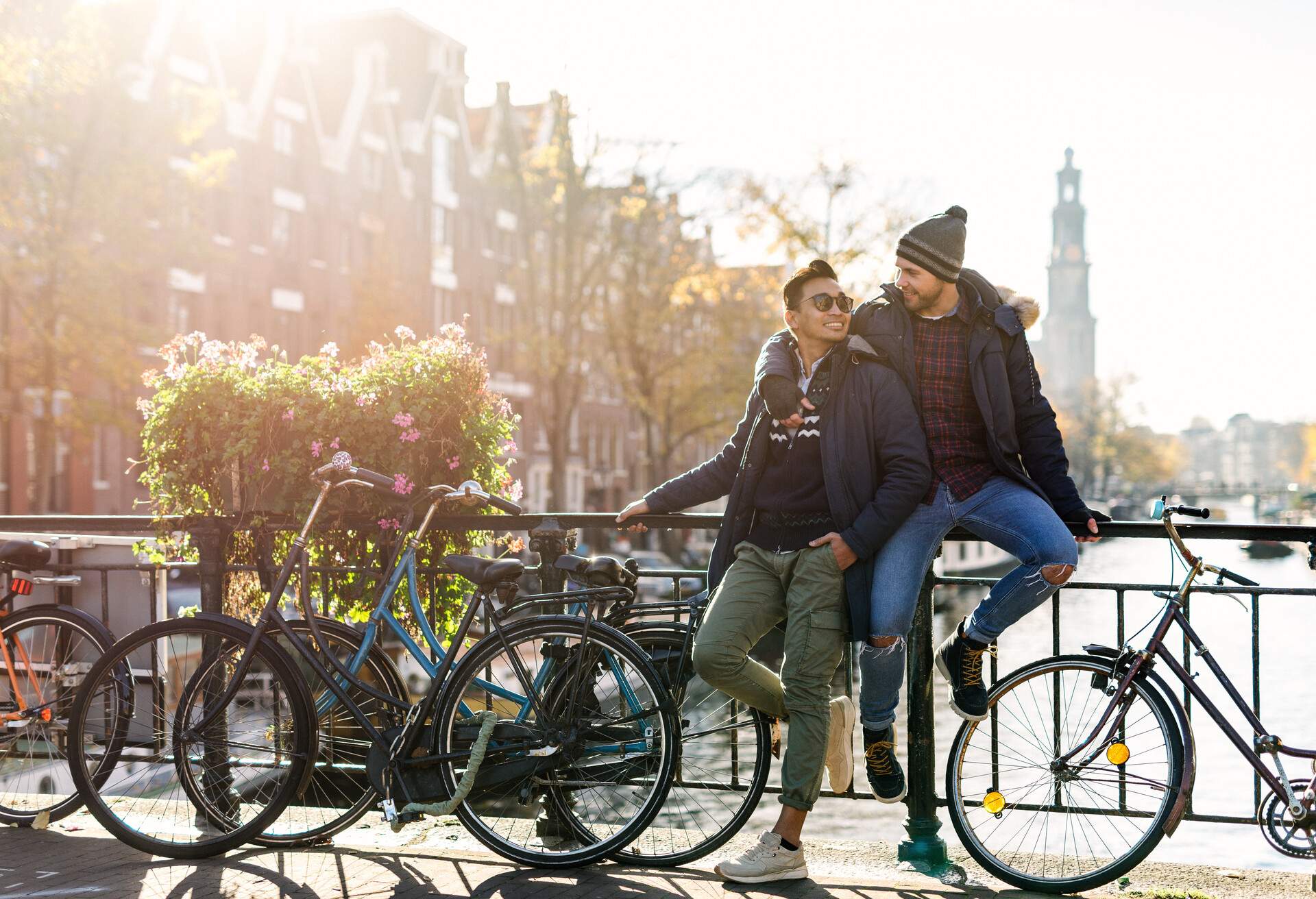 Modern gay couple enjoying the city break in late autumn or early winter in sunny Amsterdam 