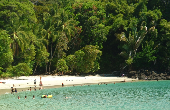 Eine kleine Gruppe Sonnenanbeter faulenzt und schwimmt am Playa Manuel Antonio, Costa Rica.