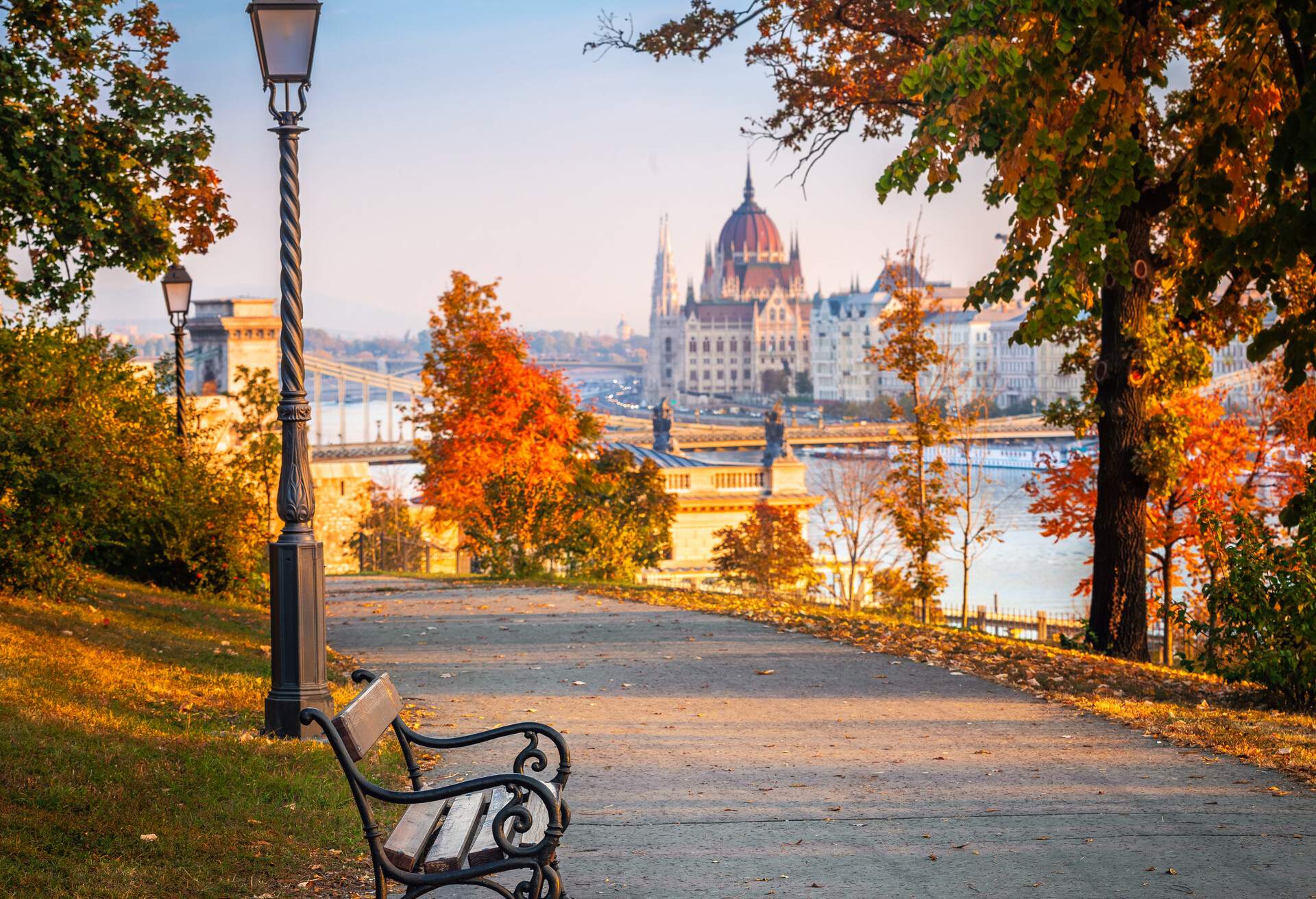 Budapest, Hungary - Romantic sunrise scene at Buda district with bench, lamp post, autumn foliage, Szechenyi Chain Bridge and Parliament at background