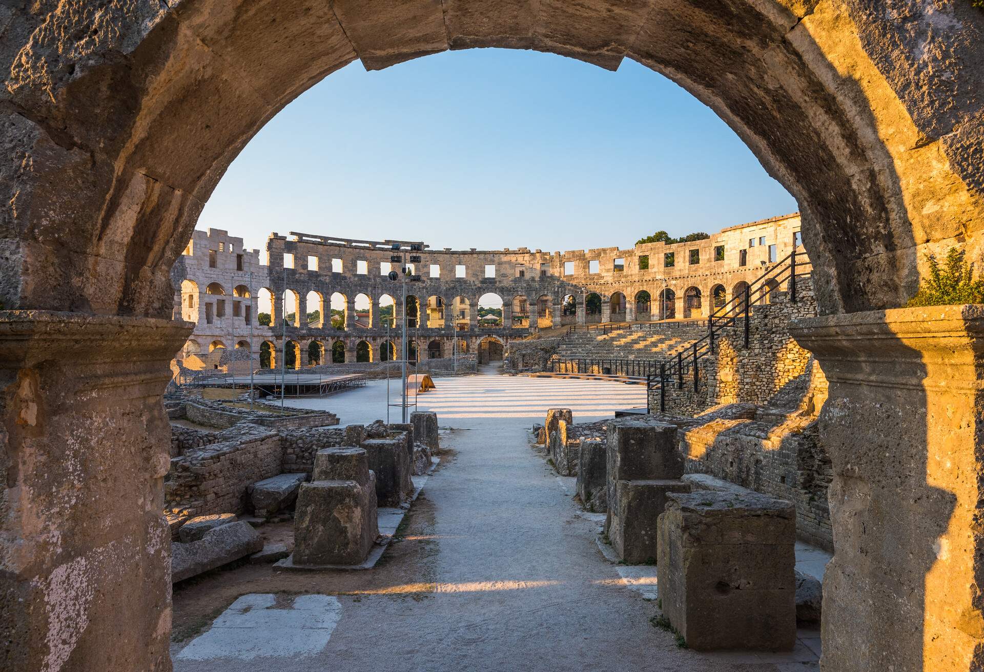 Architecture Details of the Roman Amphitheater Arena Seen through Big Round Arch in Sunny Summer Evening. Famous Travel Destination in Pula, Croatia.