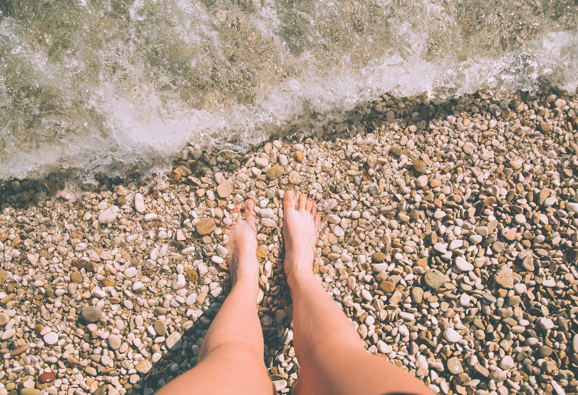 Relax on the beach. Woman's legs in the sea. A sea wave hits the feet