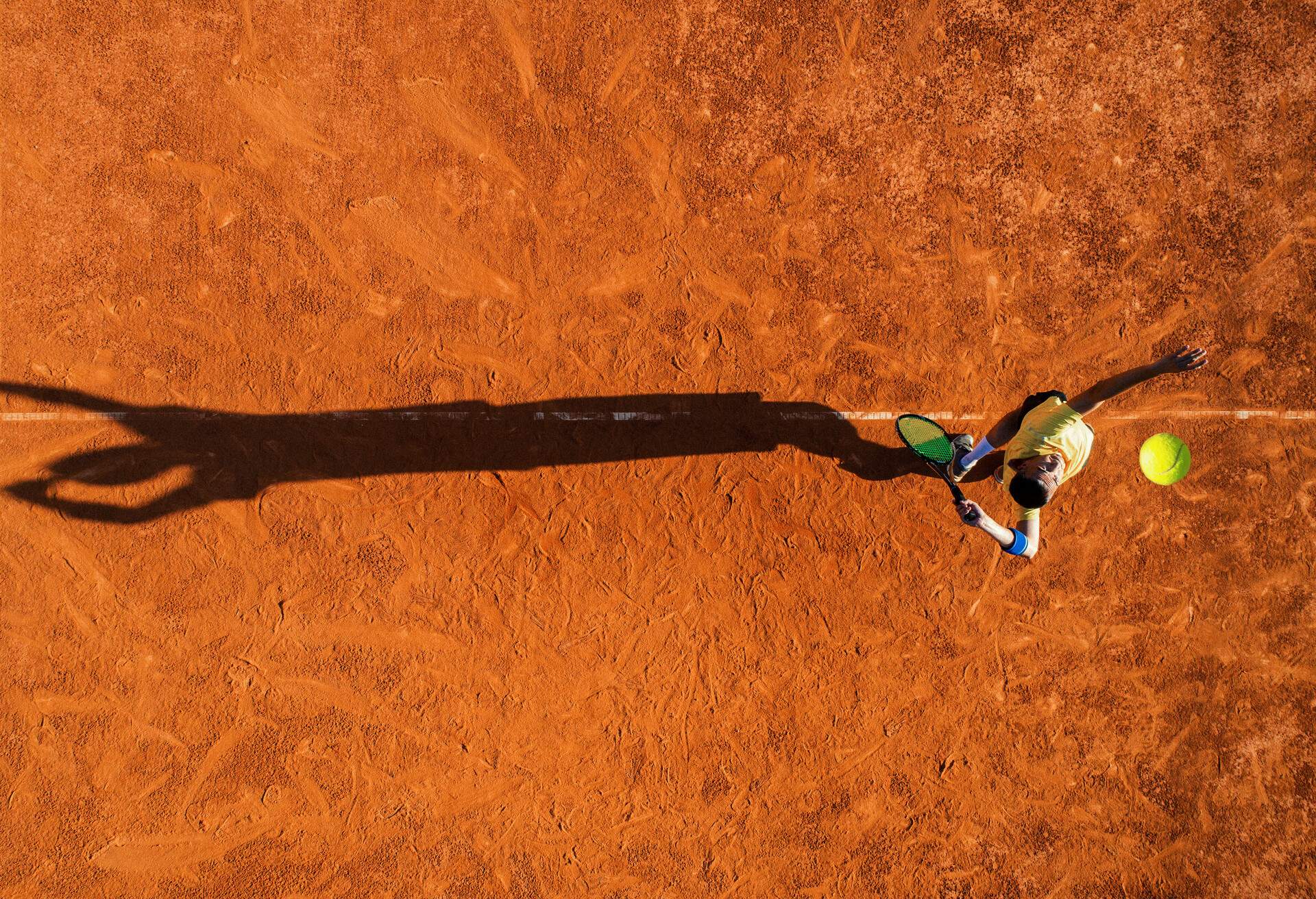 Tennis player on service. Mature adult man playing on court at sunny day.