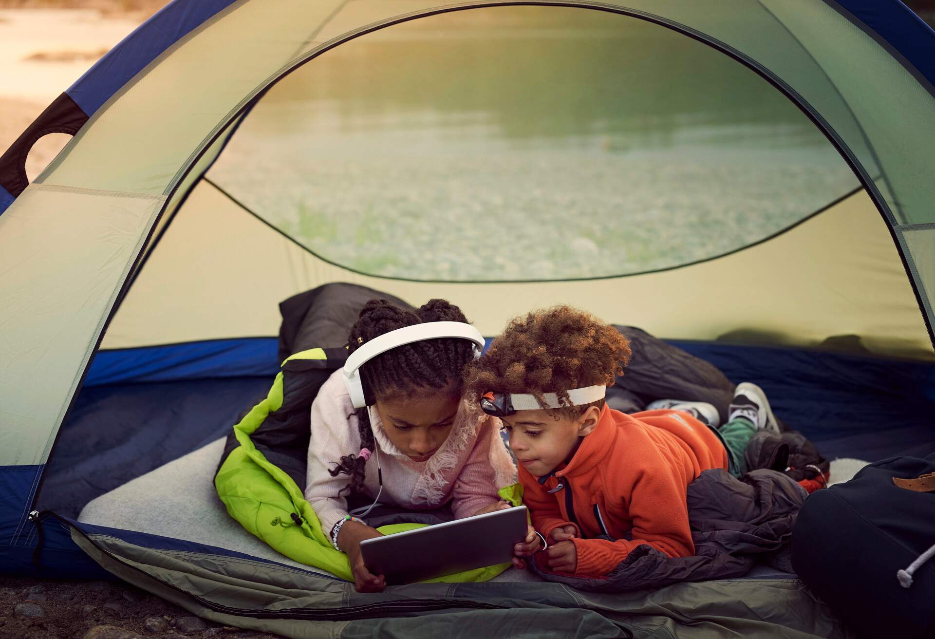 Siblings with digital tablet lying in tent