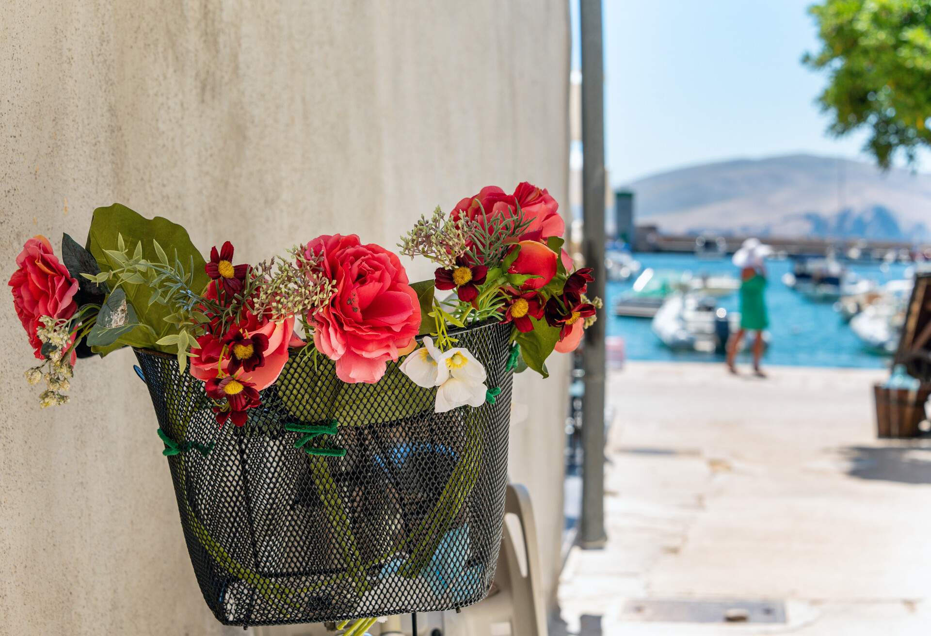 Baska old town streets decorated with flowers at summer. A women's silhouette passes by in background. Krk island, Croatia, Europe