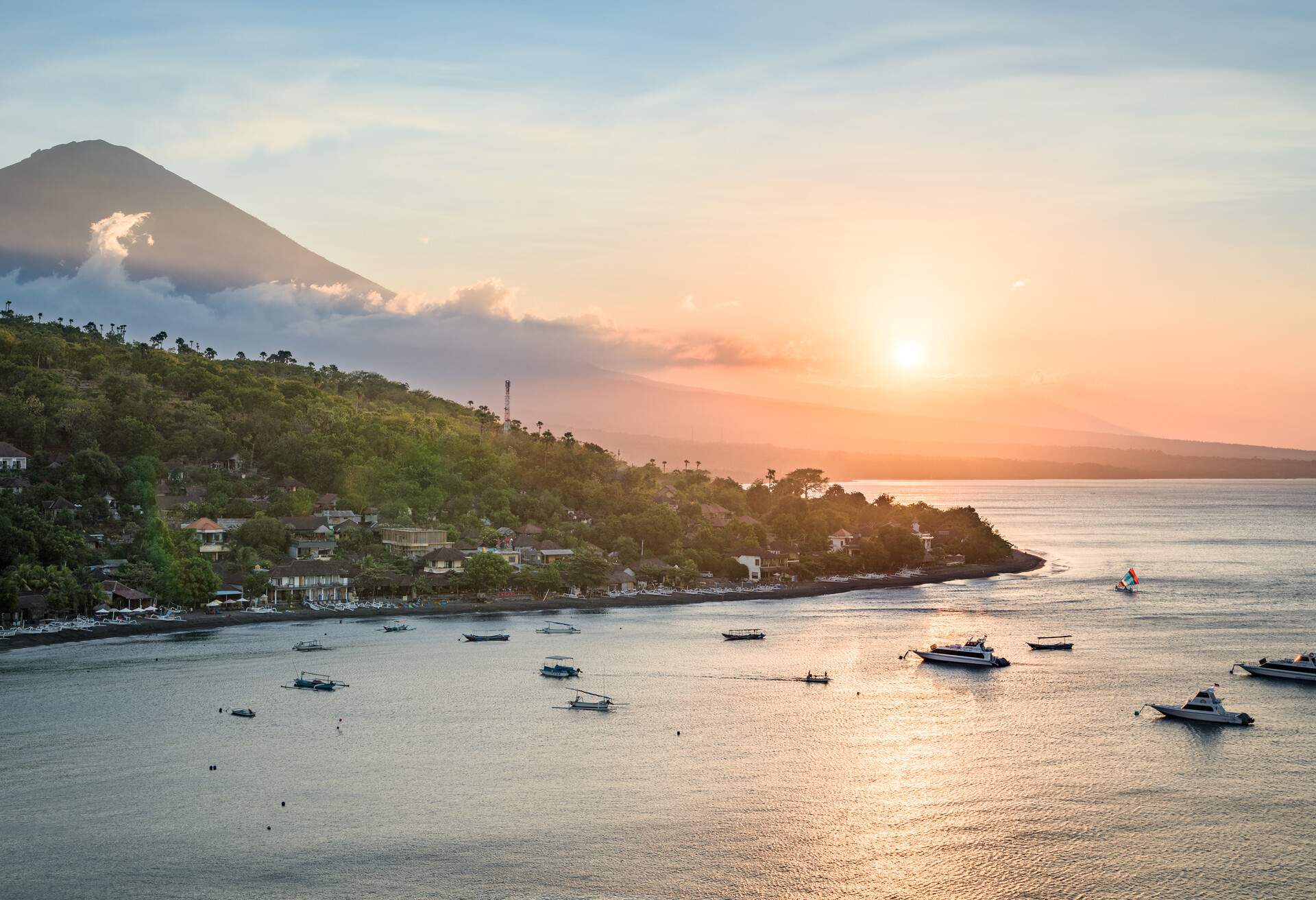 Landscape of Bali north coastline at sunrise, with Mount Agung volcano peak and forest slopes, and Java sea, from hilltop near Amed, Bali, Indonesia