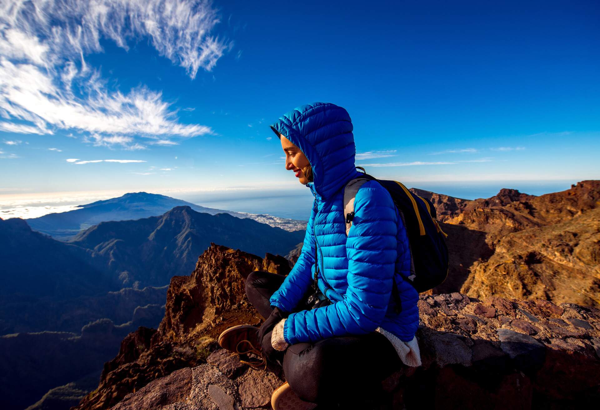 Woman in blue jacket and backpack traveling mountains near Andenes viewpoint on La Palma's island highest point in Spain