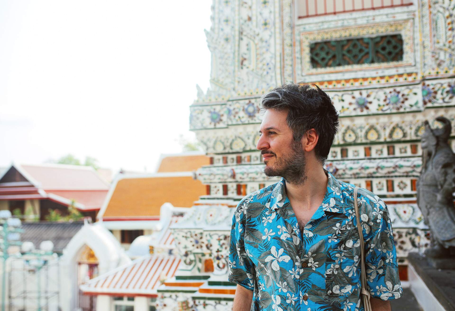 Young tourist enjoying his day in the famous Wat Pho Buddhist temple in Bangkok, Thailand. He is walking on a nice, sunny day, contemplating, enjoying the rich history of the famous place.