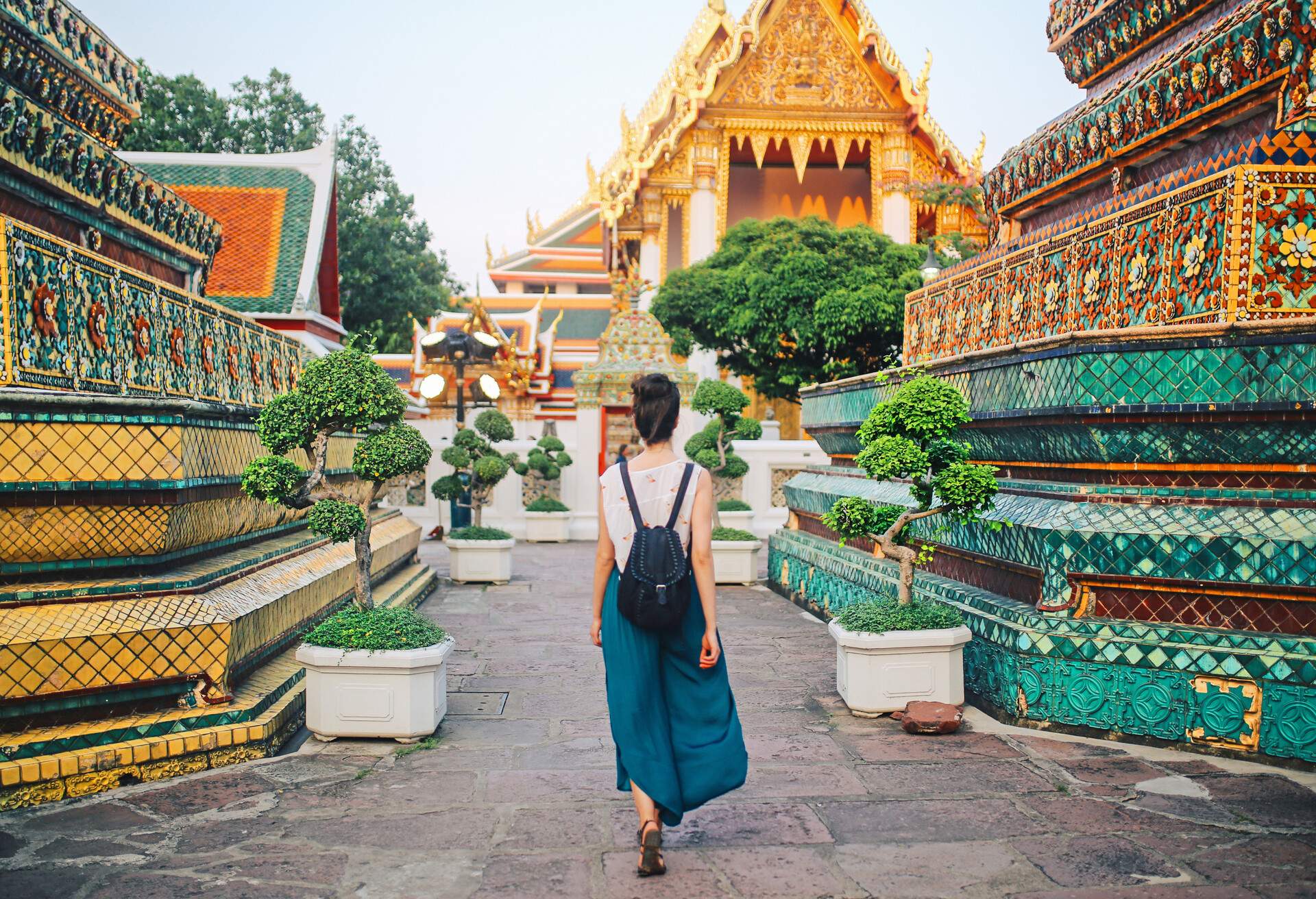 Young tourist woman enjoying her day in the famous Wat Pho Buddhist temple in Bangkok, Thailand. She is walking on a nice, sunny day, contemplating, enjoying the rich history of the famous place.