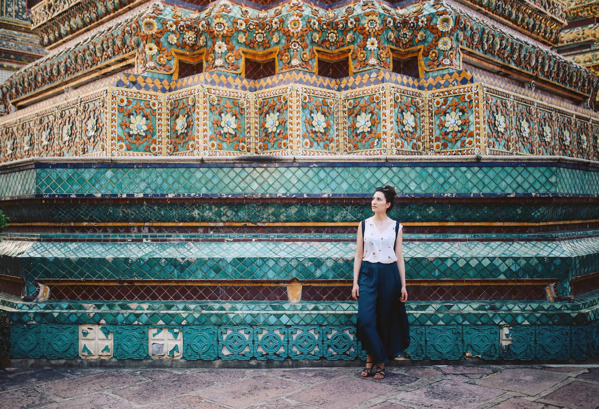 Young tourist woman enjoying her day in the famous Wat Pho Buddhist temple in Bangkok, Thailand. She is walking on a nice, sunny day, contemplating, enjoying the rich history of the famous place.