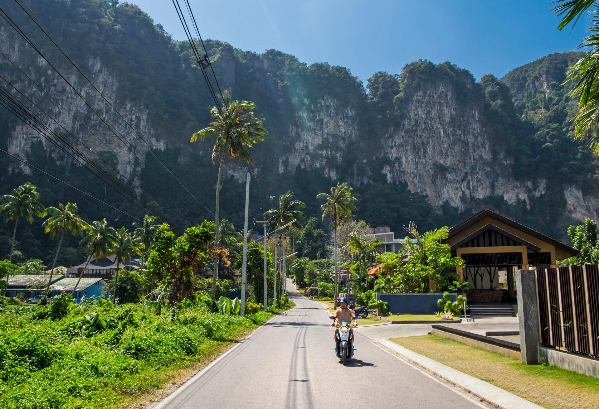 a man riding a scooter on the beautiful road in Krabi province, Thailand.