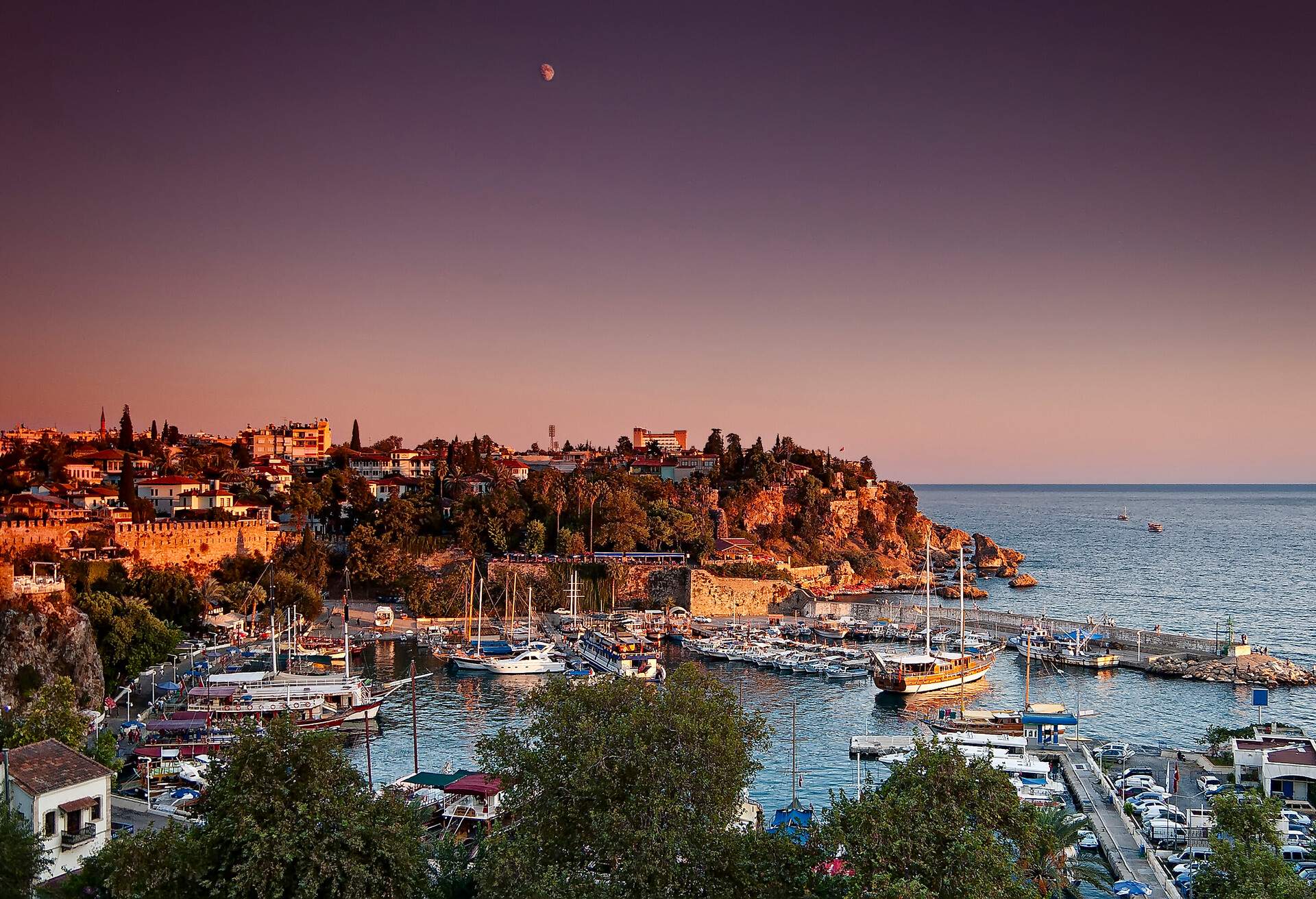 City view of old Antalya, boats in sea and historic buildings in background in Antalya, Turkey.