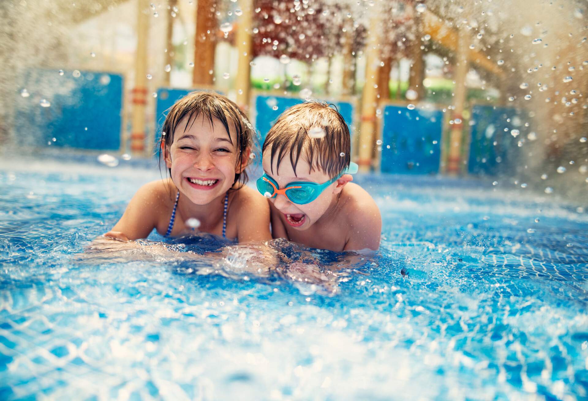 Kids playing in resort pool, about to be splashed by water from a giant bucket.