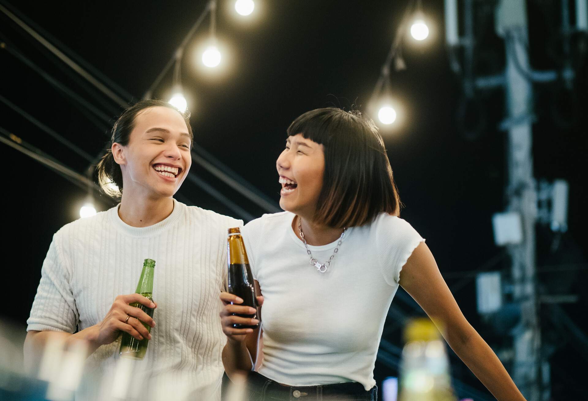 Young asian women toasting drinks with her boyfriend at a rooftop party. Young asian couple hanging out with drinks.