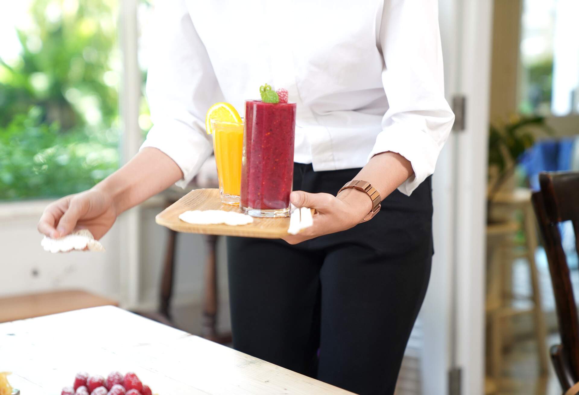 Waiter body part holding the healthy drink doing serving on the table