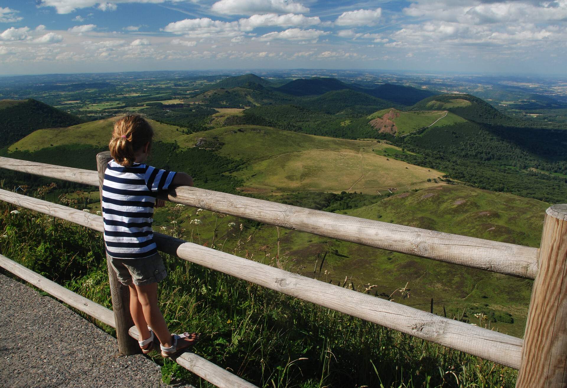 Niña mirando la panorámica de los Dômes desde la cima del volcán de Puy de Dôme, Auvergne, France.