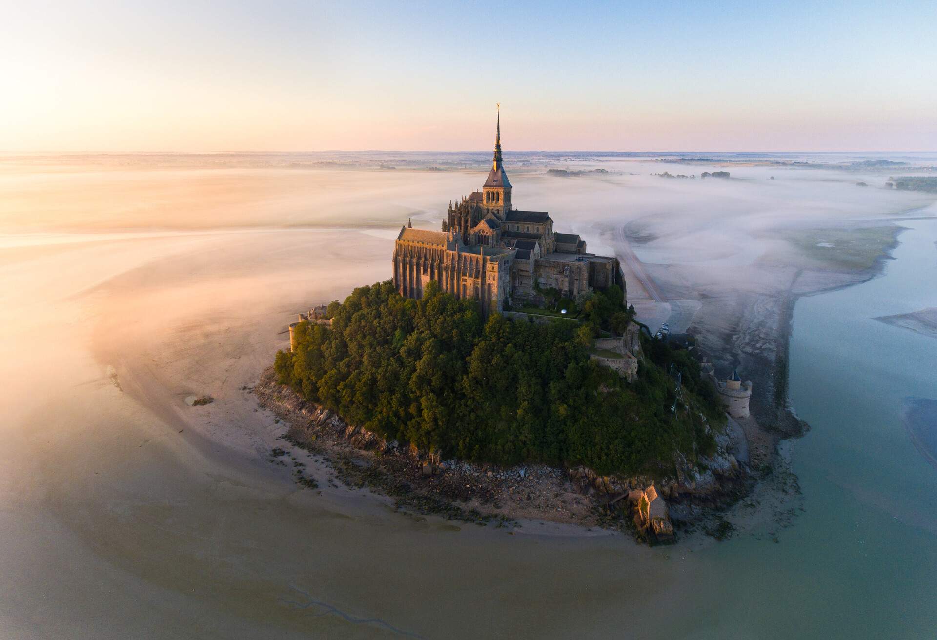 This image is taken in the Mont Saint-Michel during a pink sunrise with a little fog.