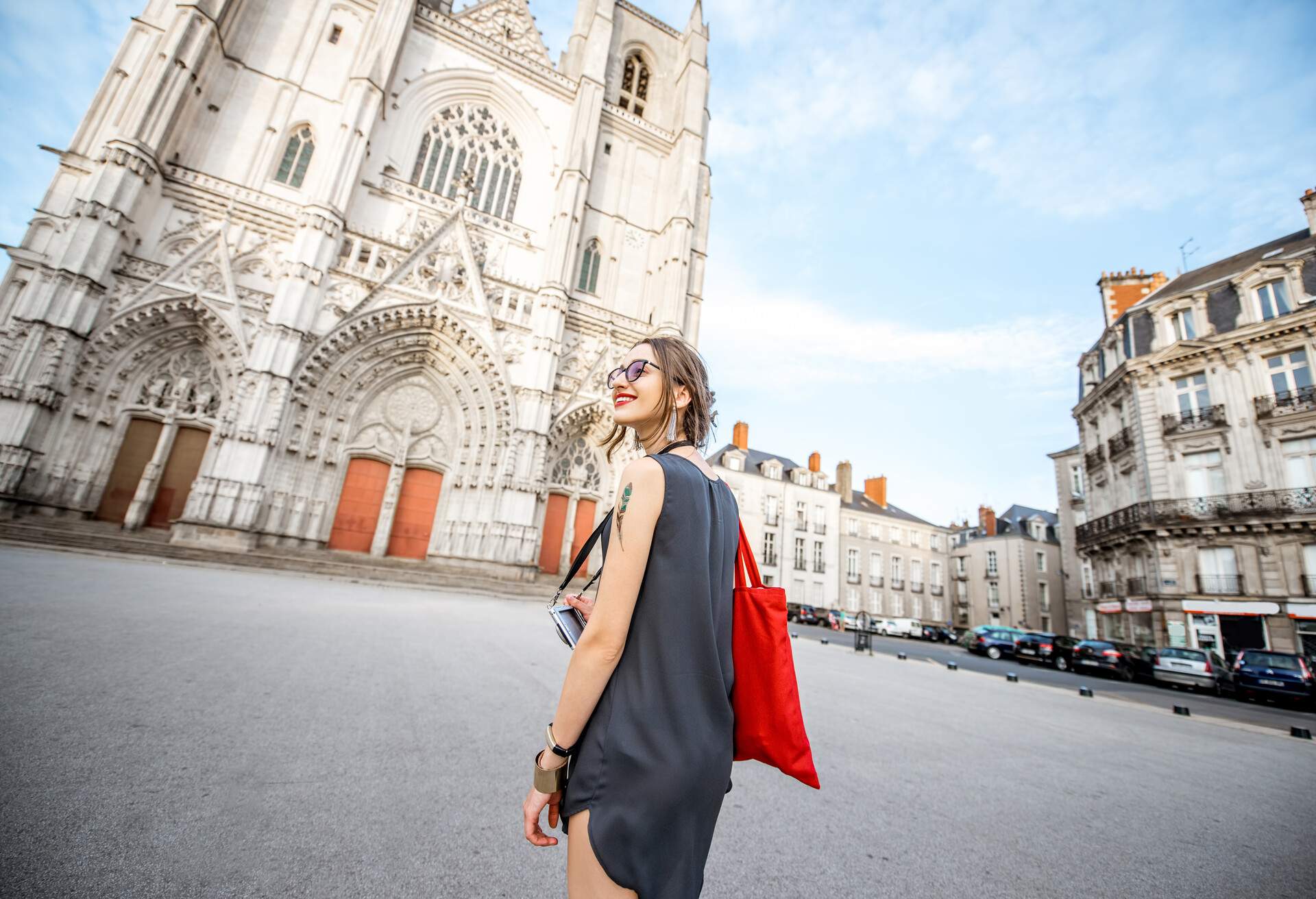 Young woman tourist walking with photo camera on saint Pierre square near the cathedral in Nantes city; Shutterstock ID 673491655; Purpose: momondo; Brand (KAYAK, Momondo, Any): mm PR overlooked cities