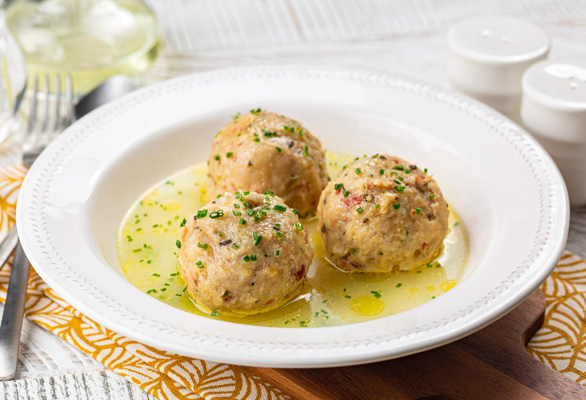 Canederli or Knödel in broth with green onion, typical pasta or dumplings for Alps, Alto Adige, German, Italian, Austrian cuisine. Made from stale bread, milk, eggs, speck.