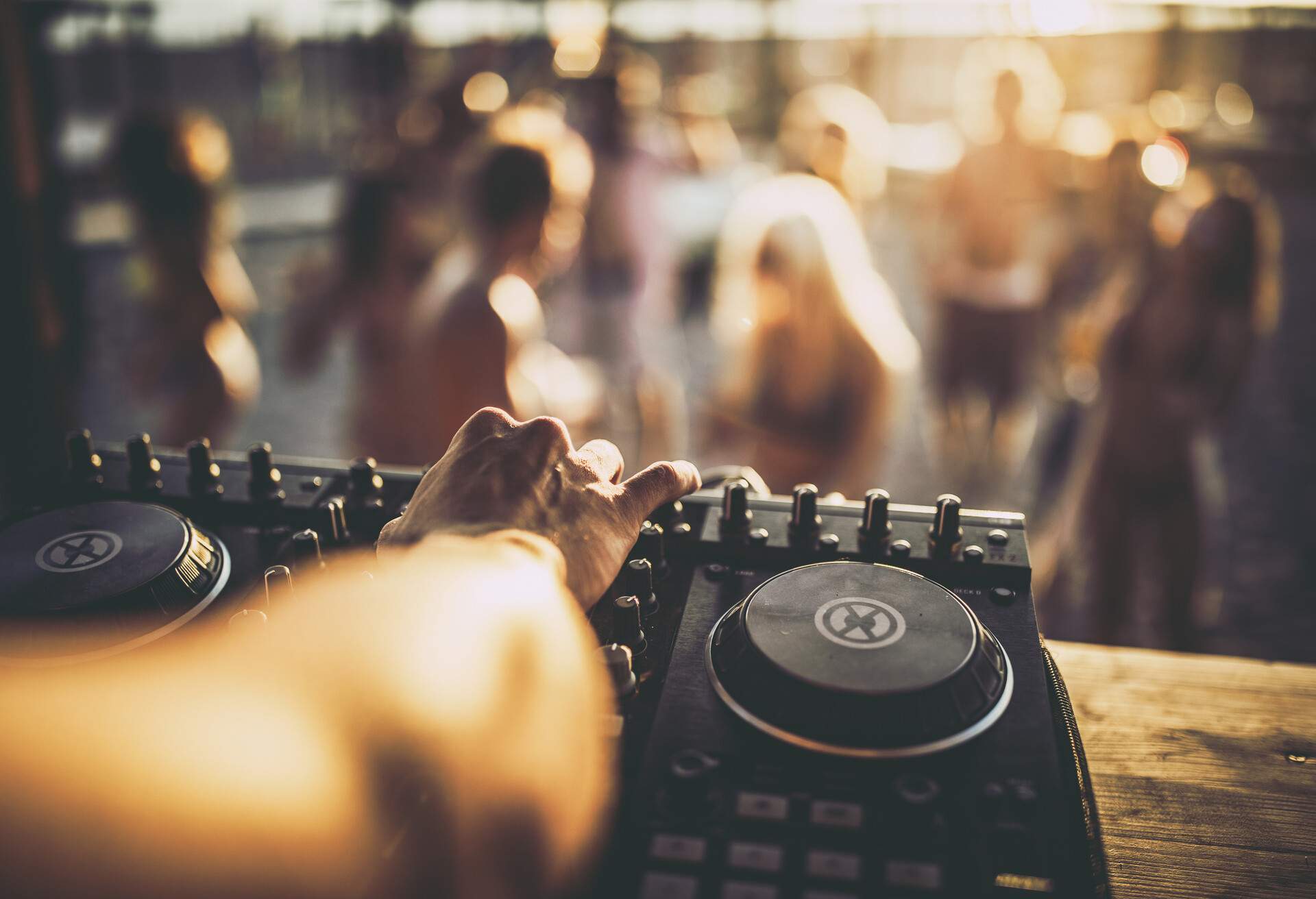 Close up of unrecognizable DJ playing music on turntable during summer beach party.