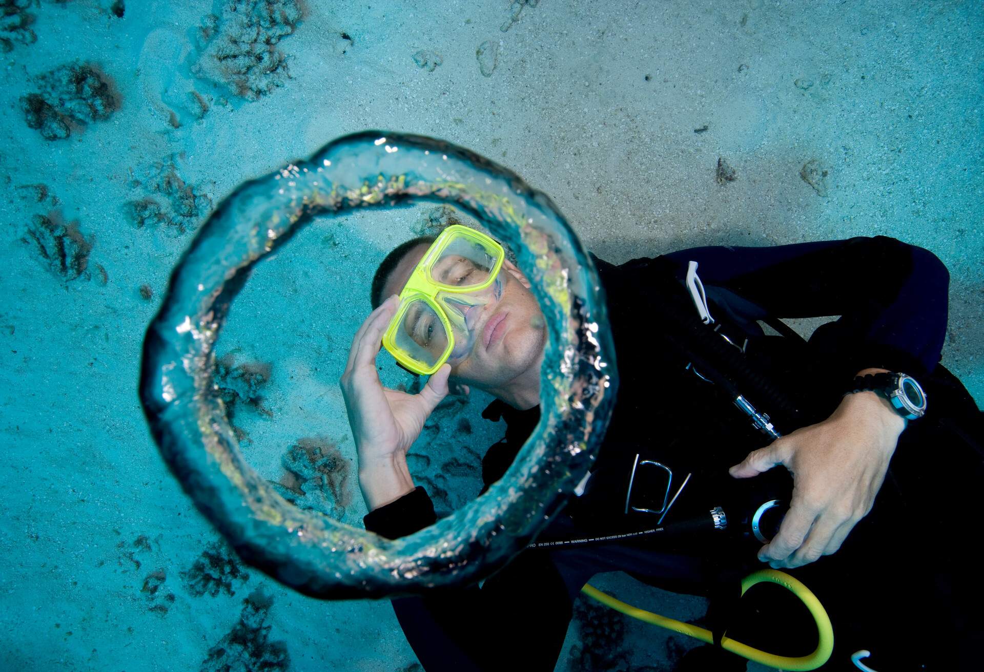 Scuba diver blows air bubble rings underwater.