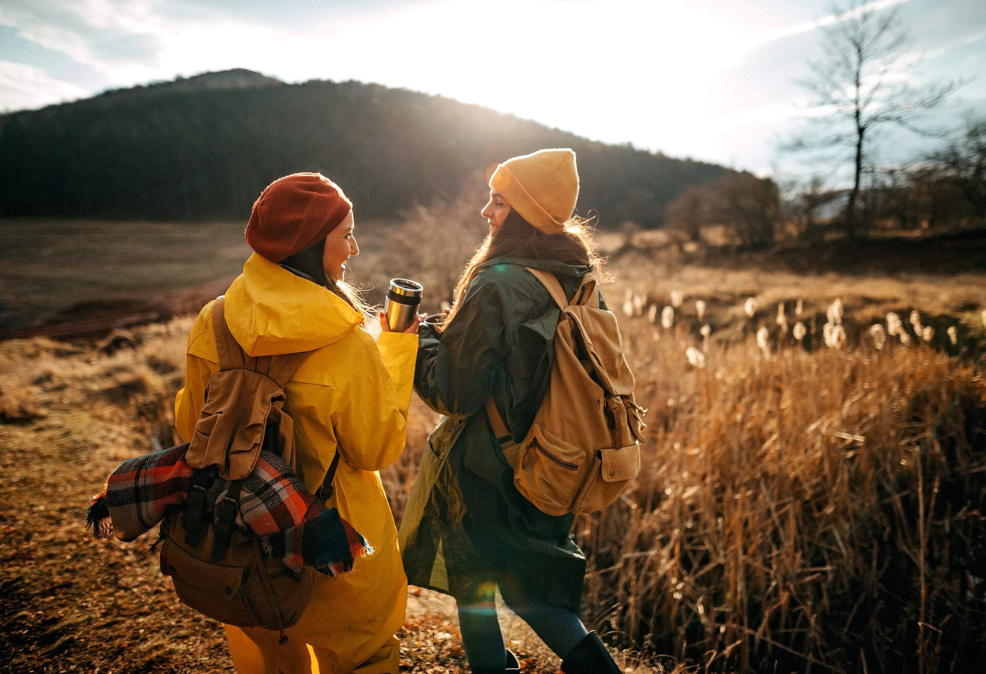 Two women relaxing in nature, they love autumn and each other, drinking hot drink