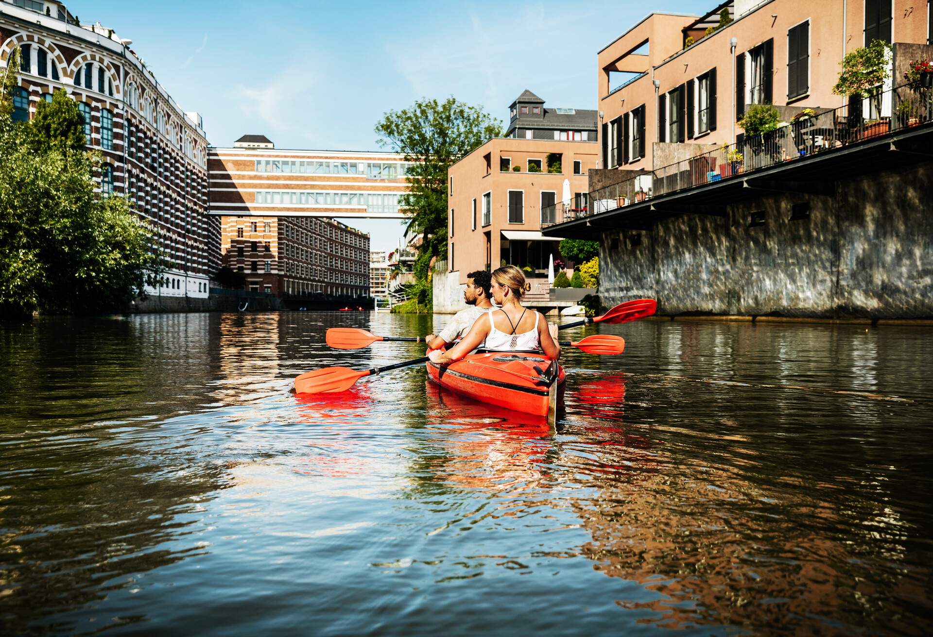 A couple are exploring the inner city canals, paddling in a kayak together.