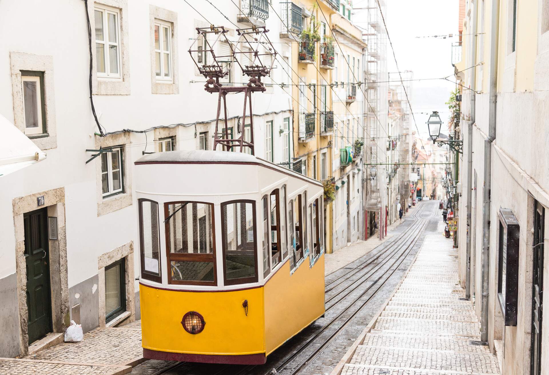 Typical yellow old tram funicular Elevador da Bica in Bairro Alto, going up hill in the old town of Lisbon
