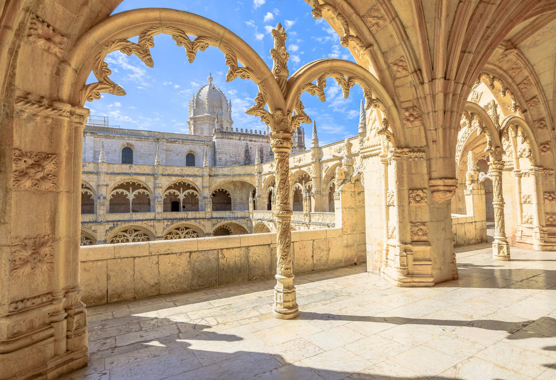 Beautiful reticulated vaulting on courtyard or cloisters of Hieronymites Monastery, Mosteiro dos Jeronimos, famous Lisbon landmark in Belem district and Unesco Heritage. Church dome on background.