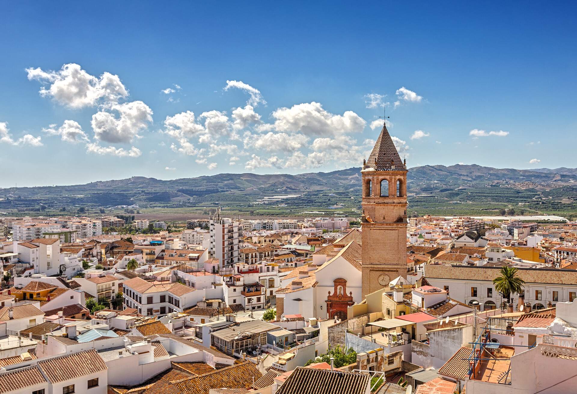 A picturesque old town with a cone-shaped bell tower rising above the buildings. 