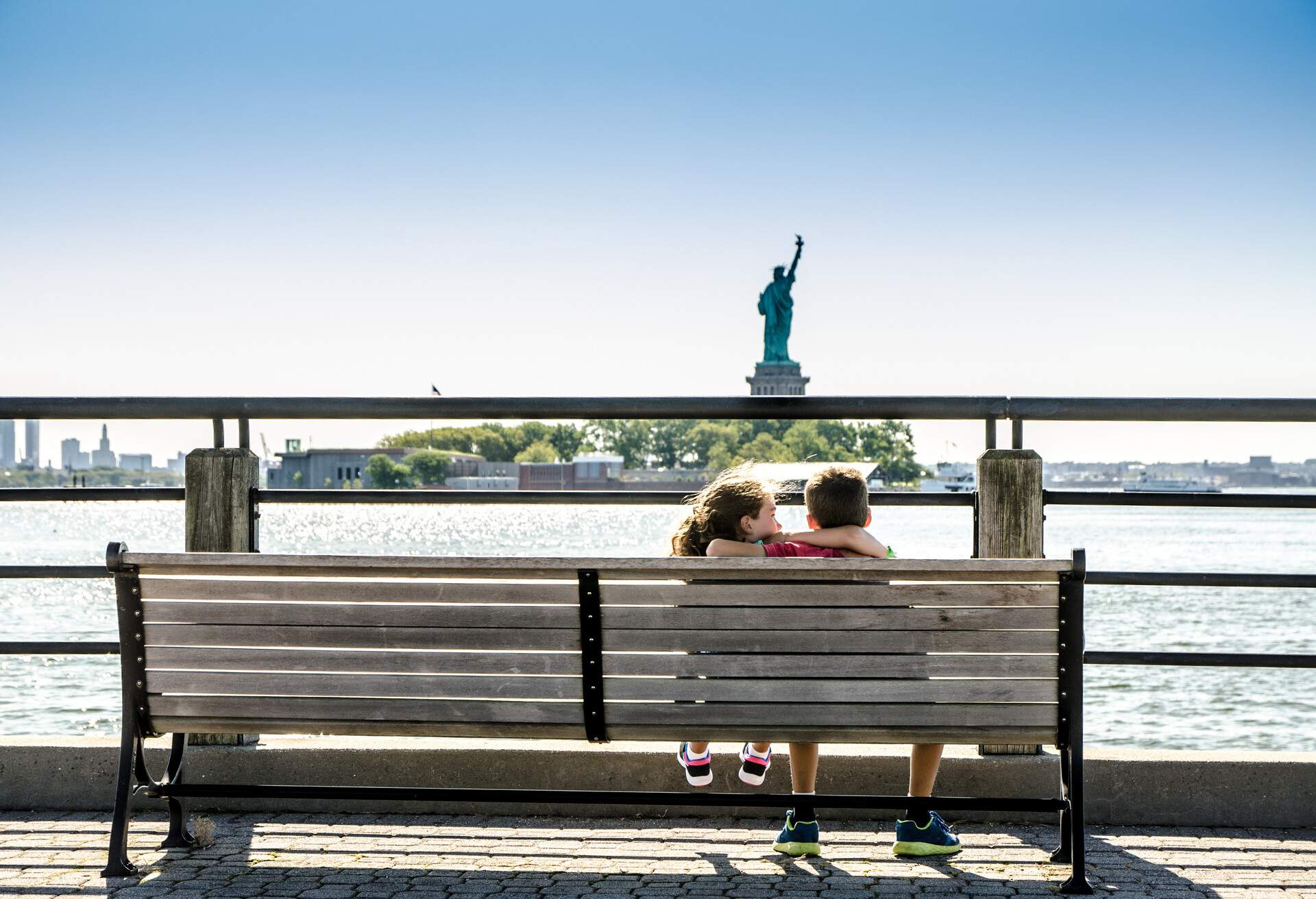 Two kids looking at Statue of Liberty from the Liberty State Park in Jersey city during summer day