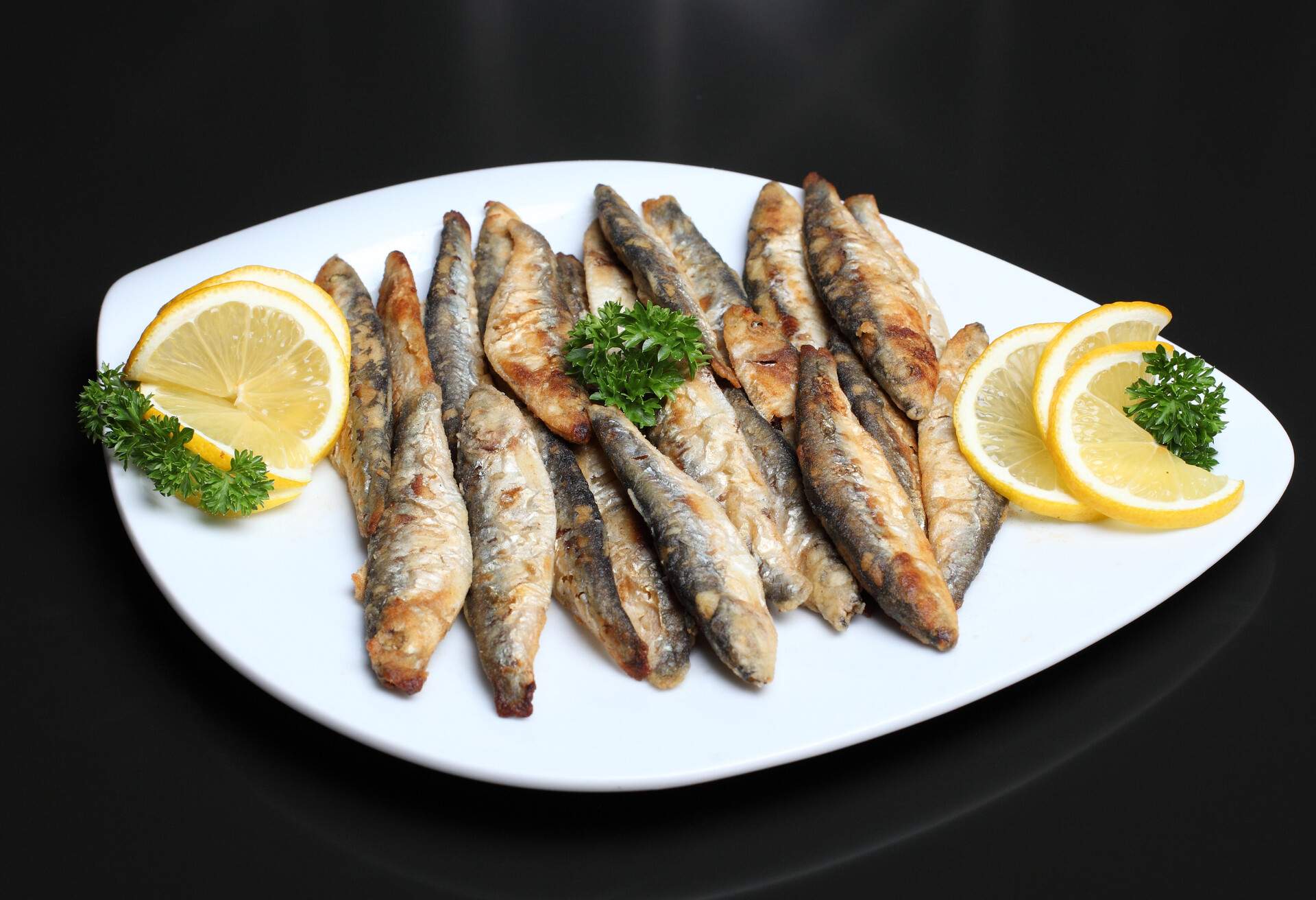 Fried anchovies with lettuce salad and lemon in a dish