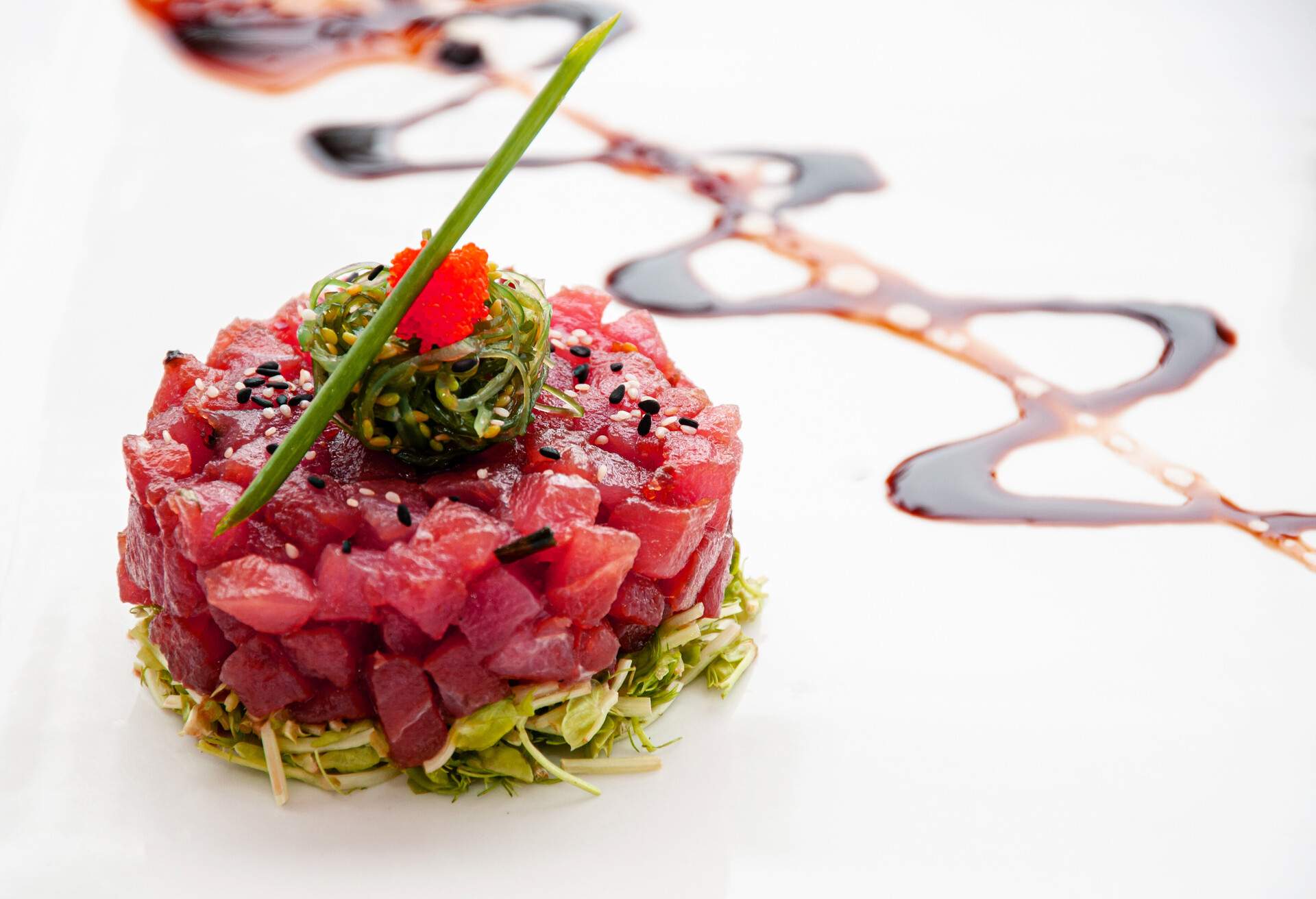 Fresh Tuna tartare sesame seaweed and green salad and balsamic reduction sauce and tropical fruits salsa in white plate