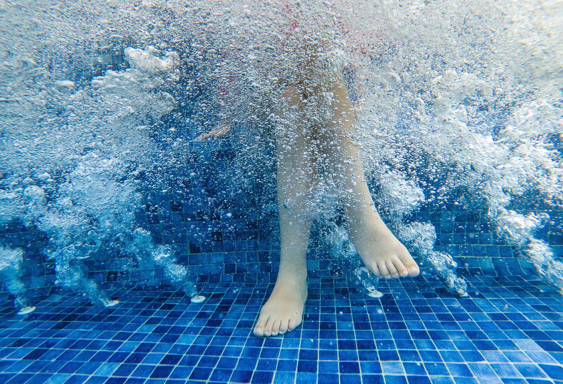 Teenager girl relaxing at SPA. Cross legs near air flow underwater bubbles.