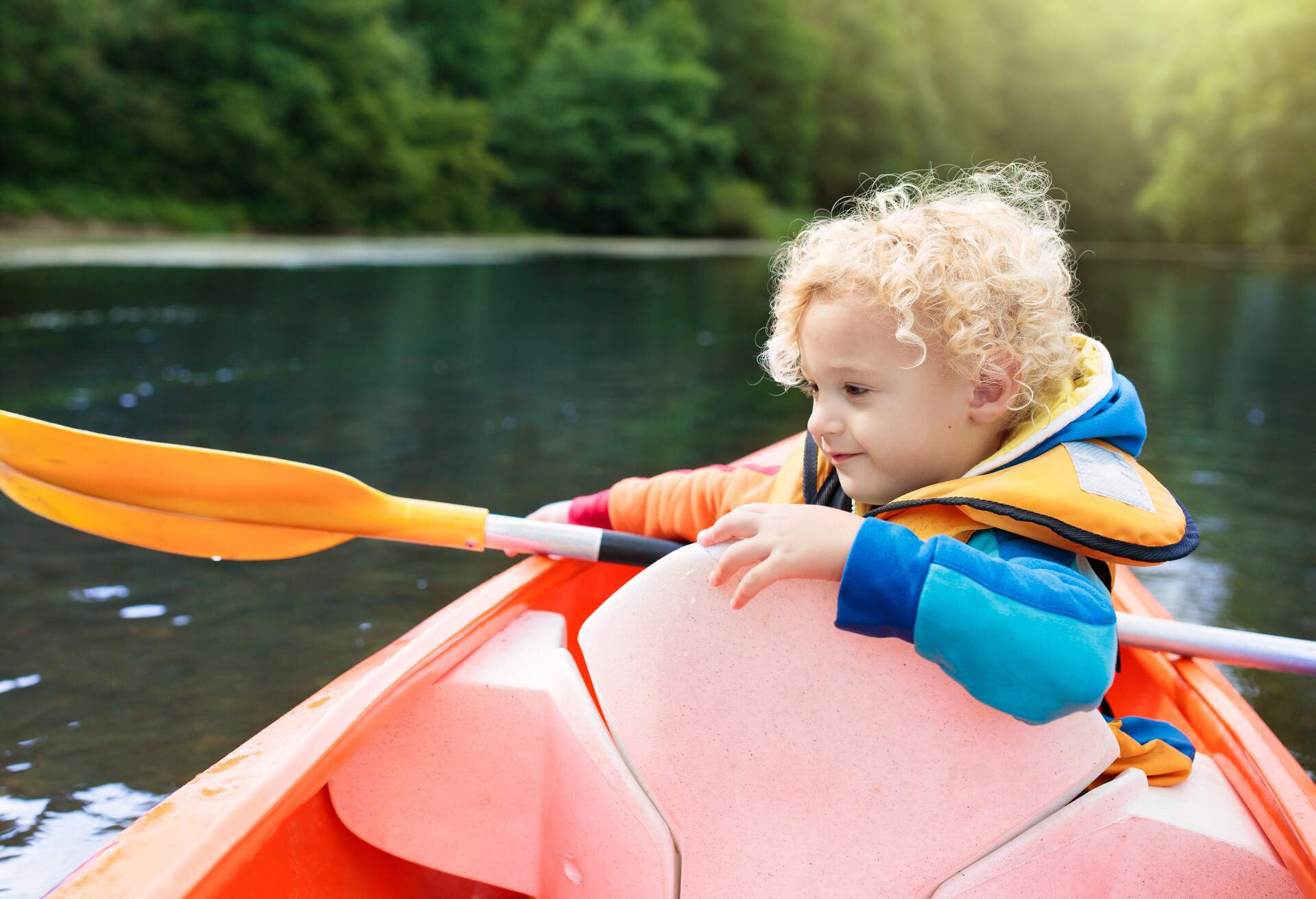 Child with paddle on kayak. Summer camp for kids. Kayaking and canoeing with family. Children on canoe. Little boy on kayak ride. Wild nature and water fun on summer vacation. Camping and fishing.