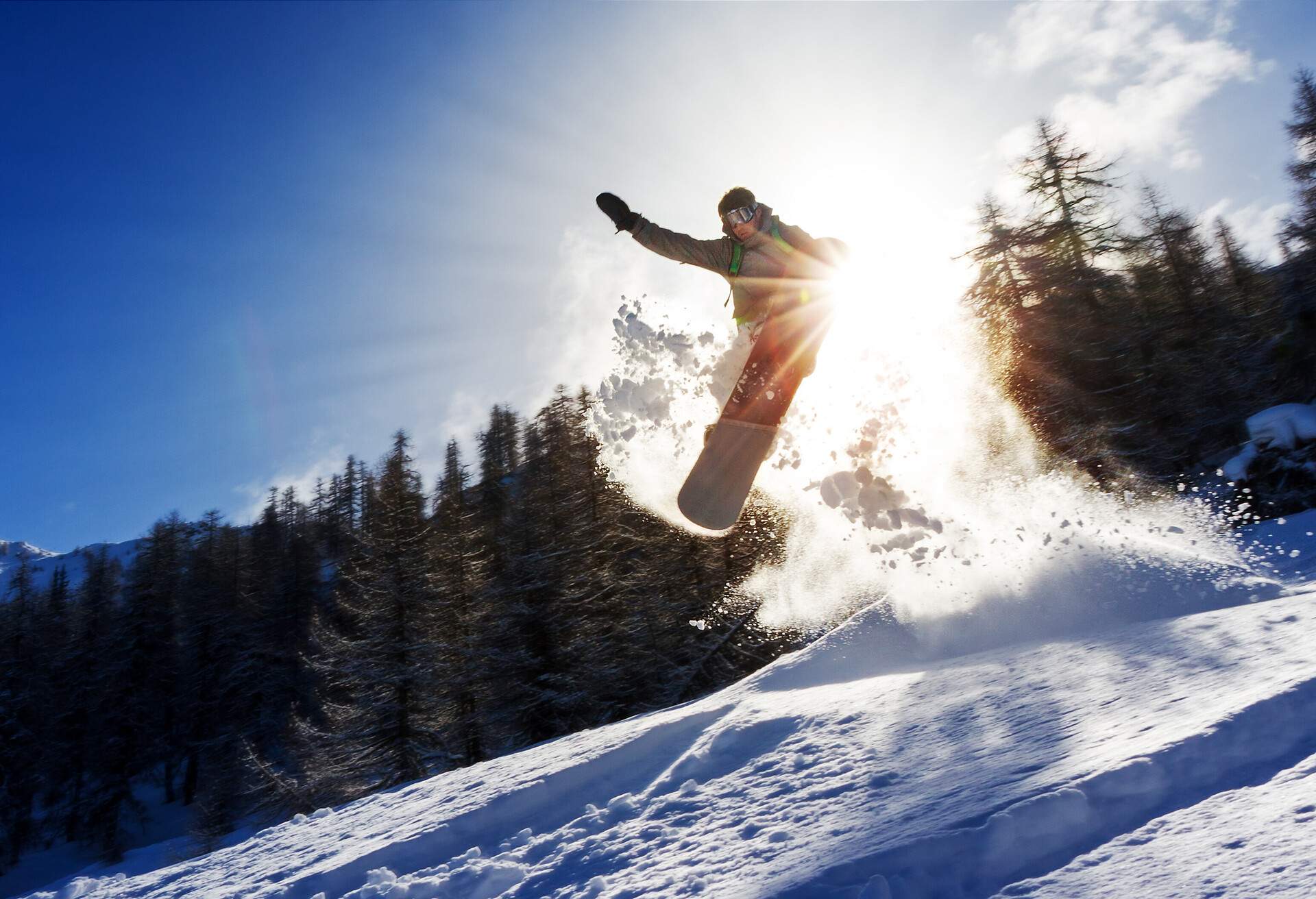 Powerful image of a snowboarder jumping over a kicker in the backcountry powder