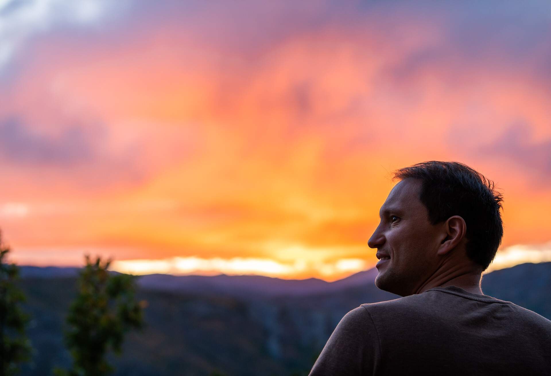 Aspen, Colorado rocky mountains colorful sunset in blurry background with back of young man looking at view at twilight