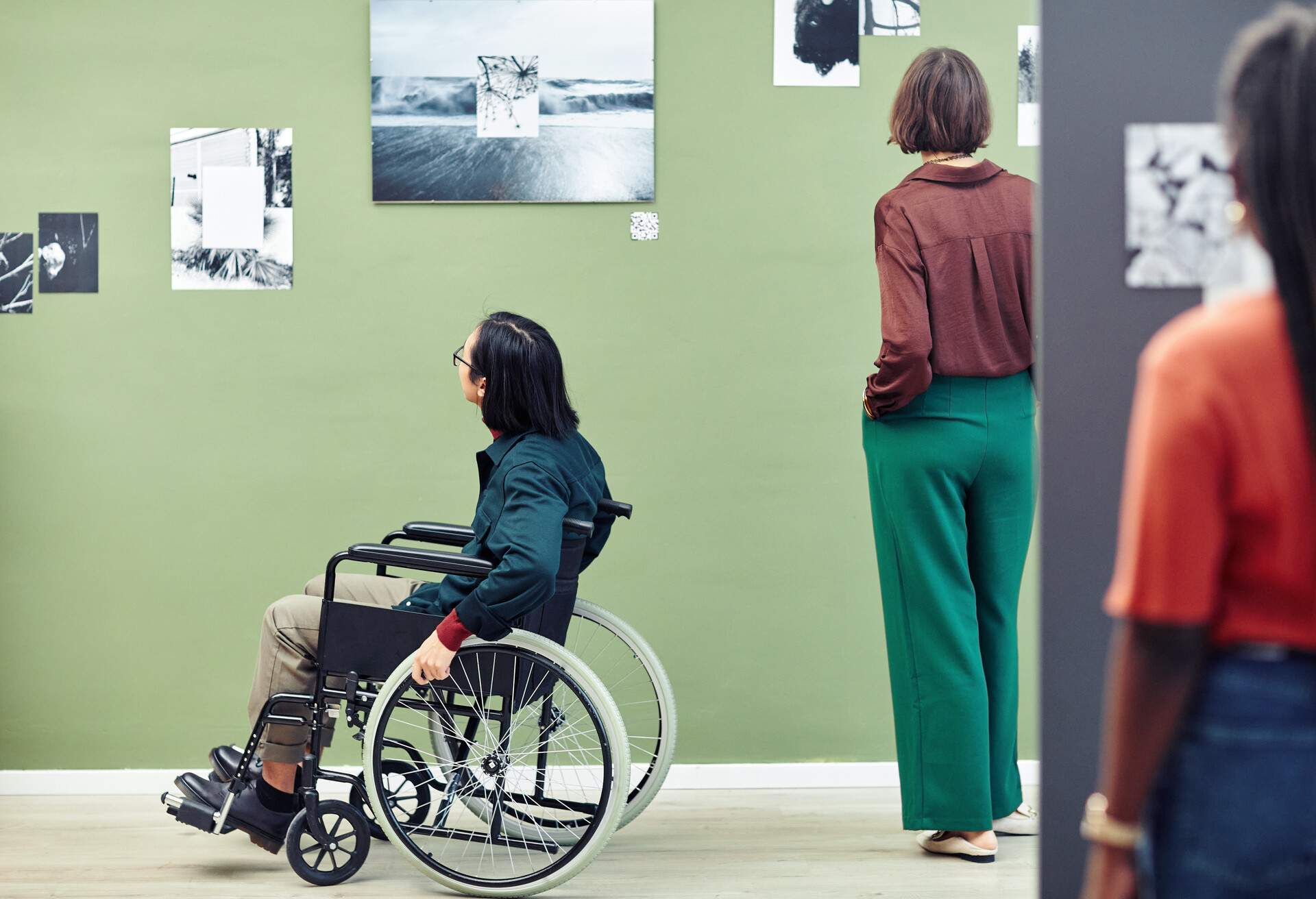 Unrecognizable ethnically diverse young people looking at black and white pictures on walls at contemporary photography exhibition in university