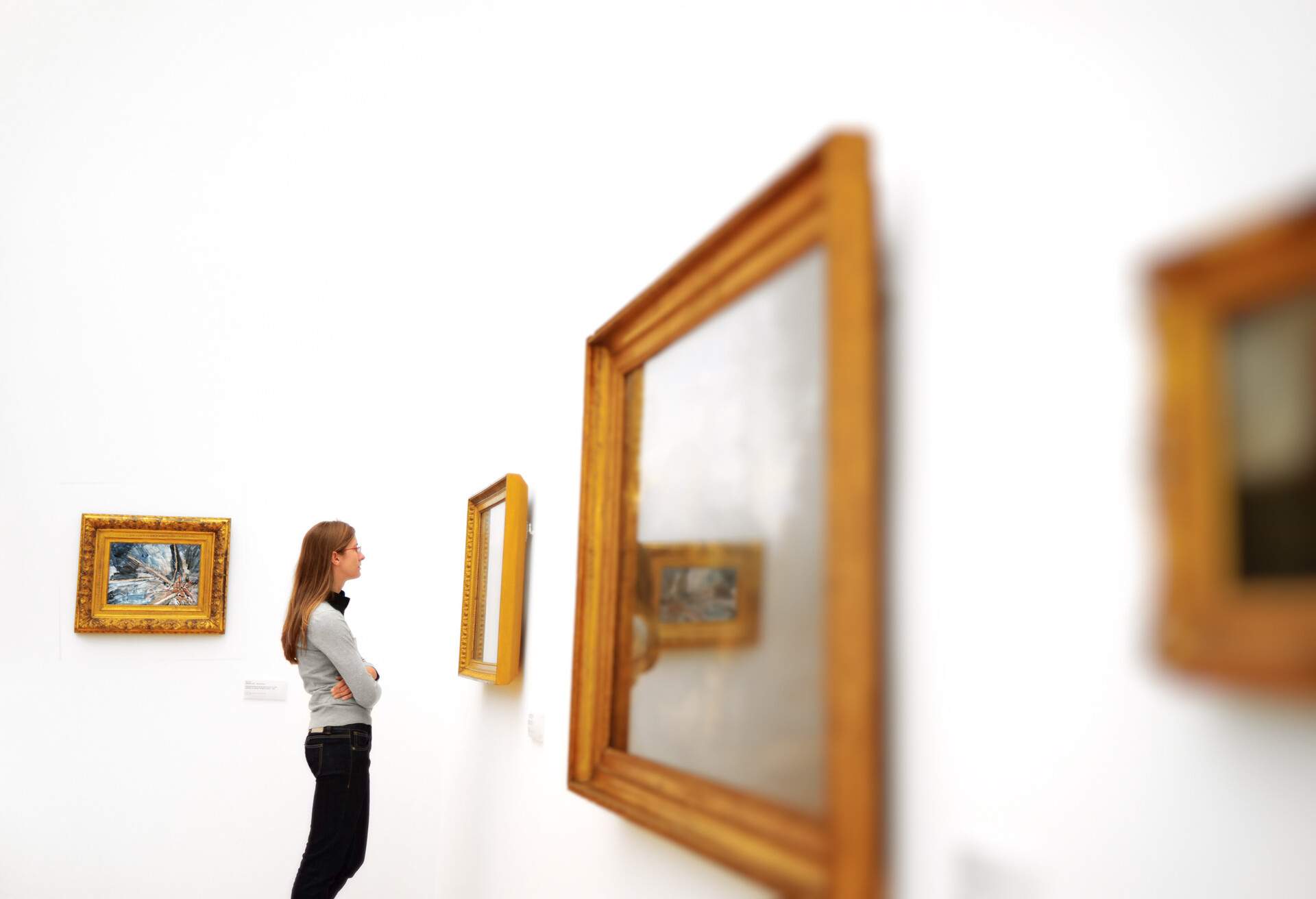 woman in a museum looking at pictures on the wall.