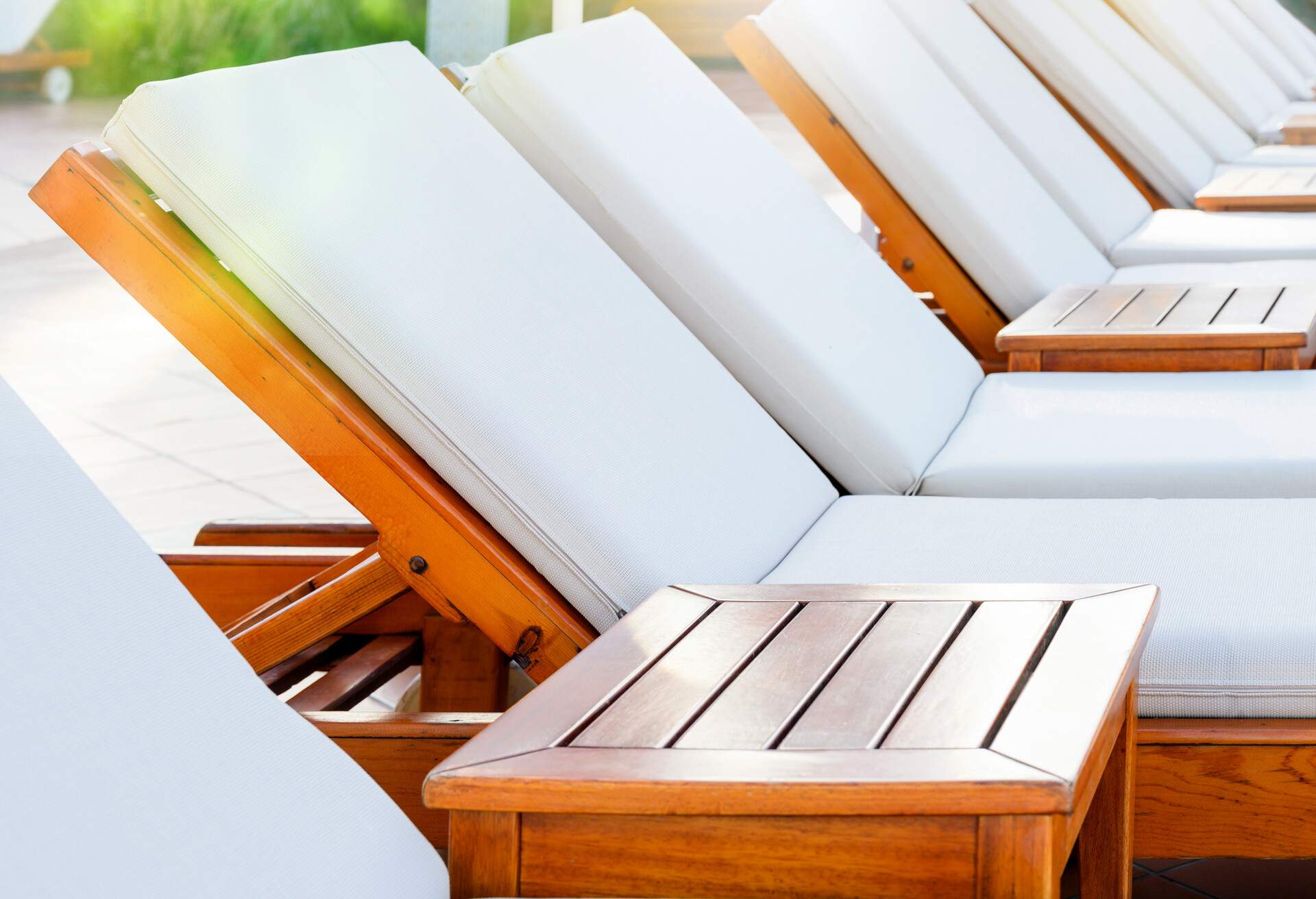 Blank white wooden loungers in a row in luxury hotel. Sunbed for sunbathing in the inn.