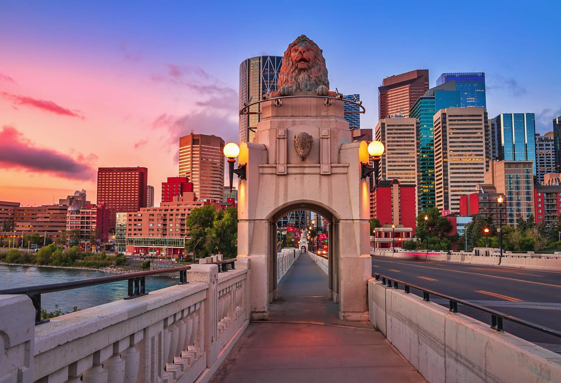 A scenic view of a walkway leading towards downtown Calgary under a colorful sunrise sky.